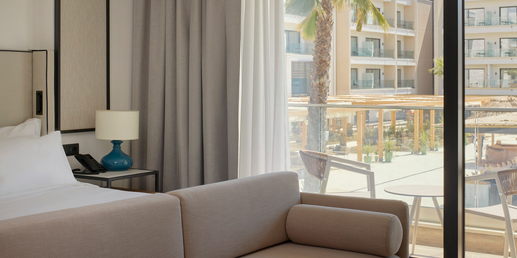 a couch in a room with a balcony and palm trees