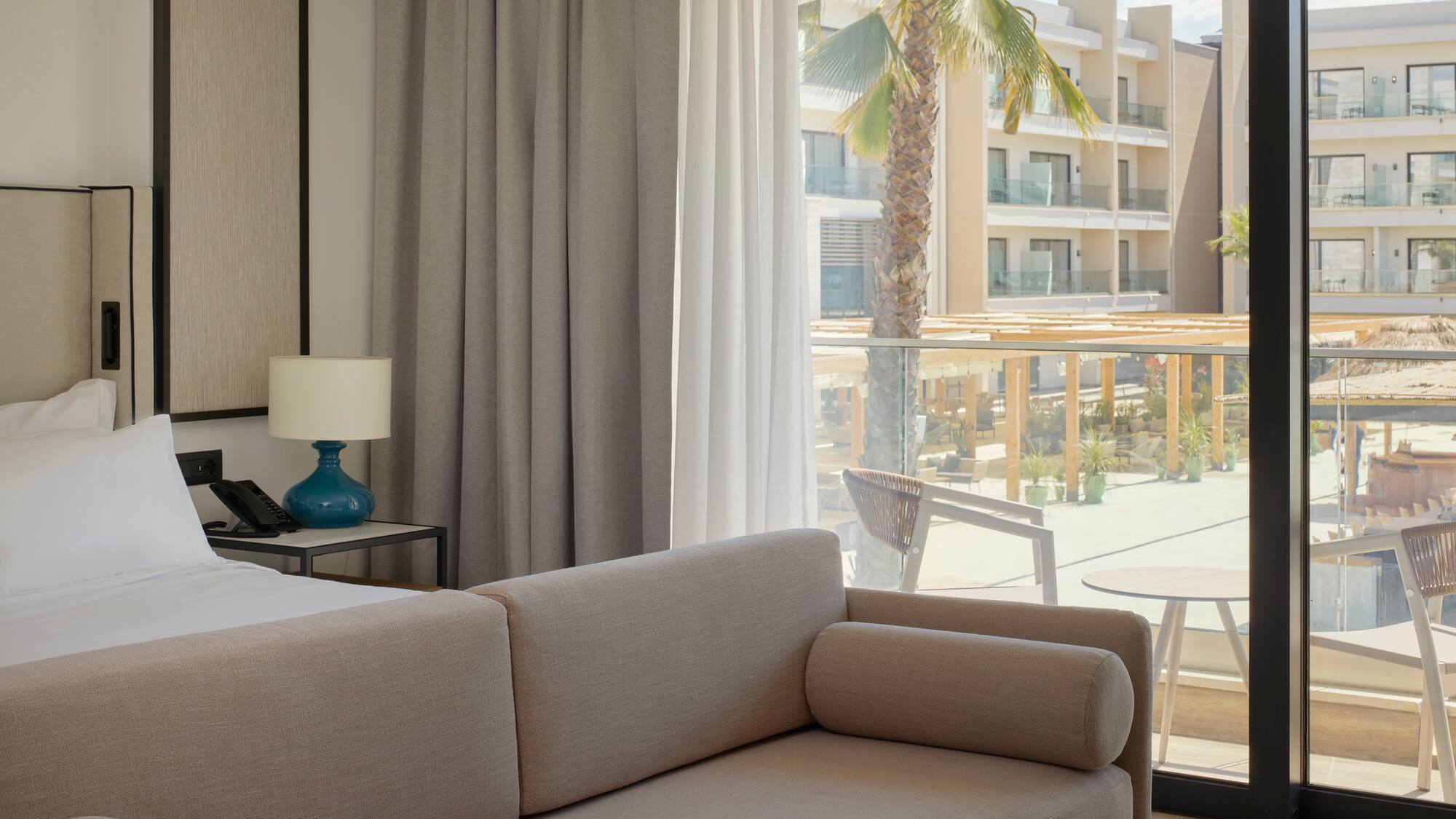 a couch in a room with a balcony and palm trees