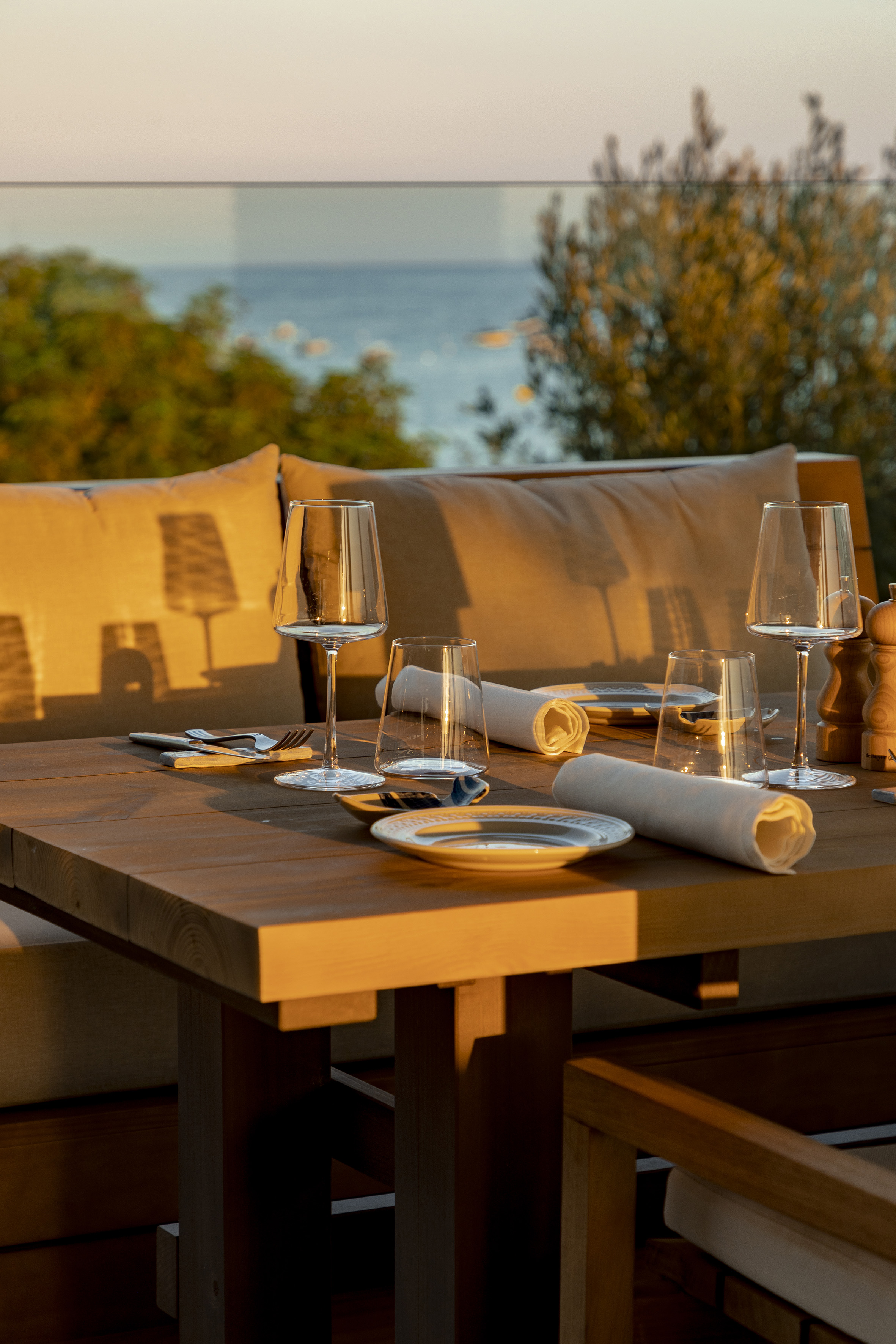 Elegant outdoor dining table set at sunset with sea view.