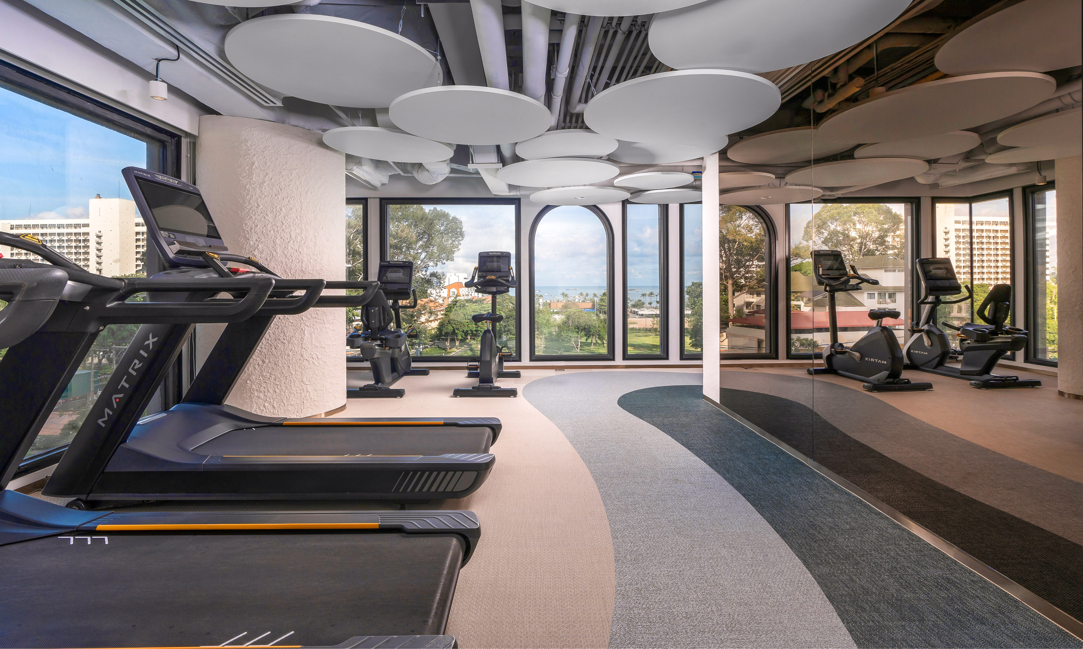 Bright modern gym with treadmills, exercise bikes, and large scenic windows.