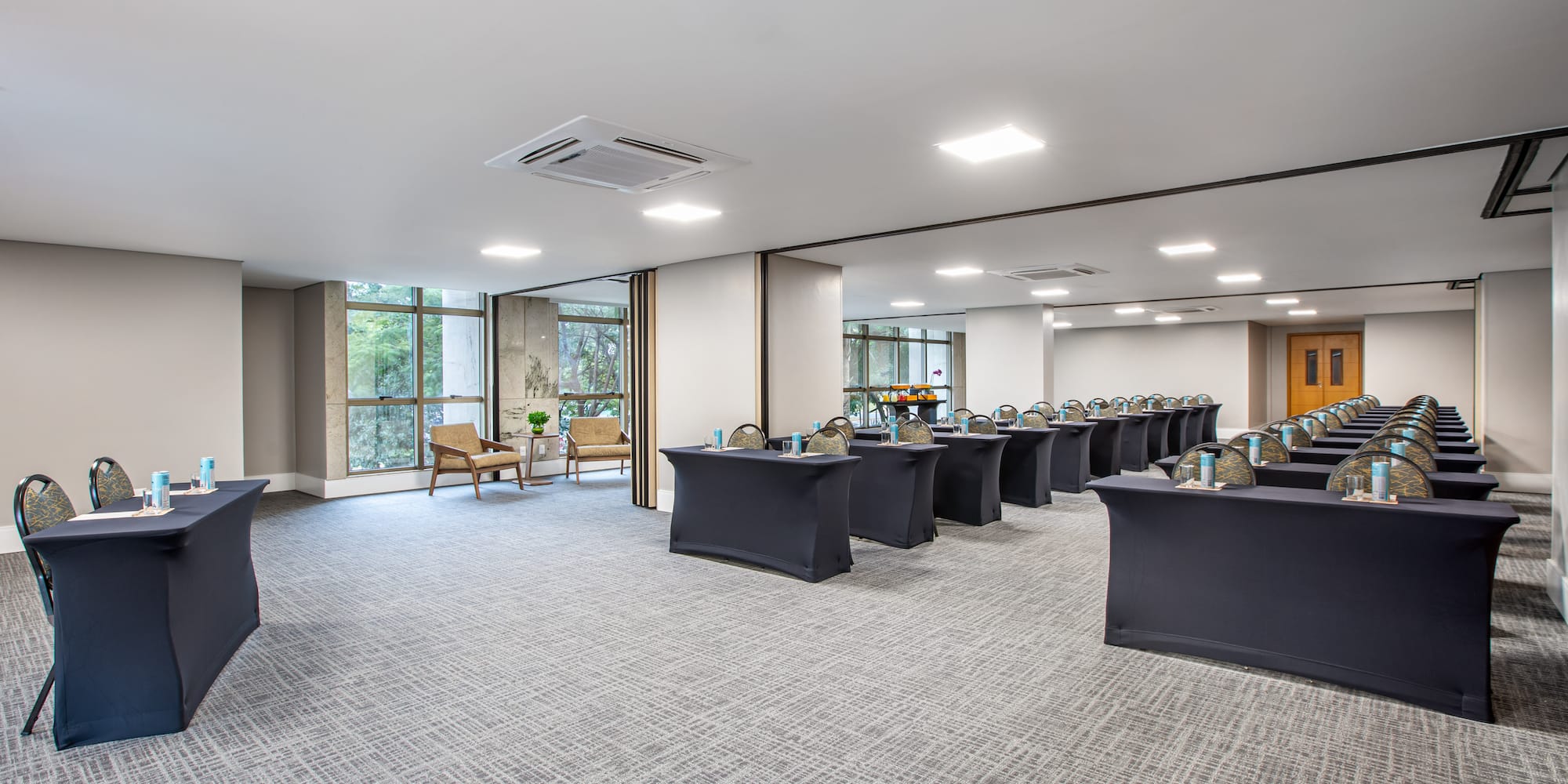 Modern conference room with classroom setup, dark tables, chairs, and large windows.