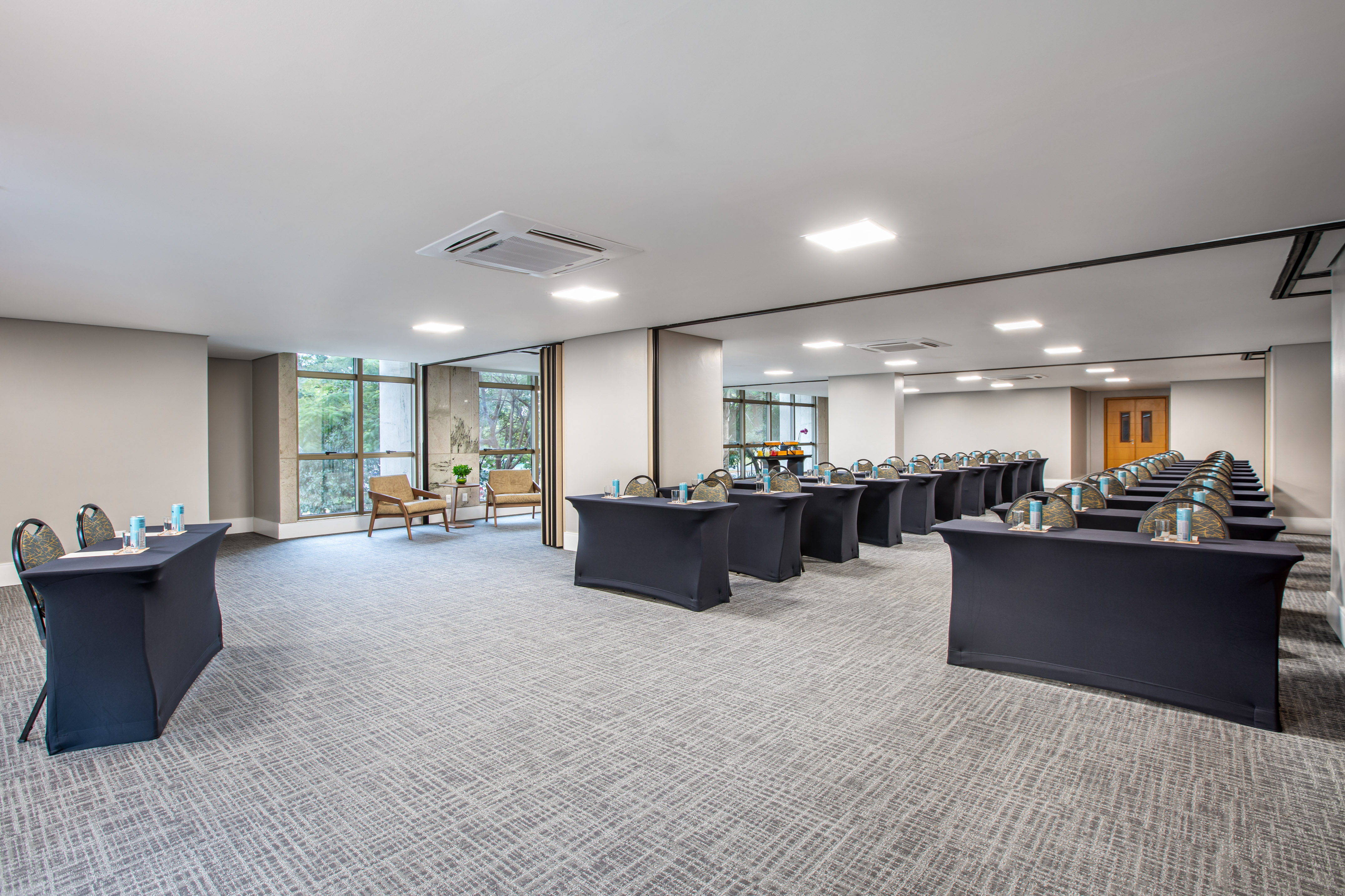 Modern conference room with classroom setup, dark tables, chairs, and large windows.
