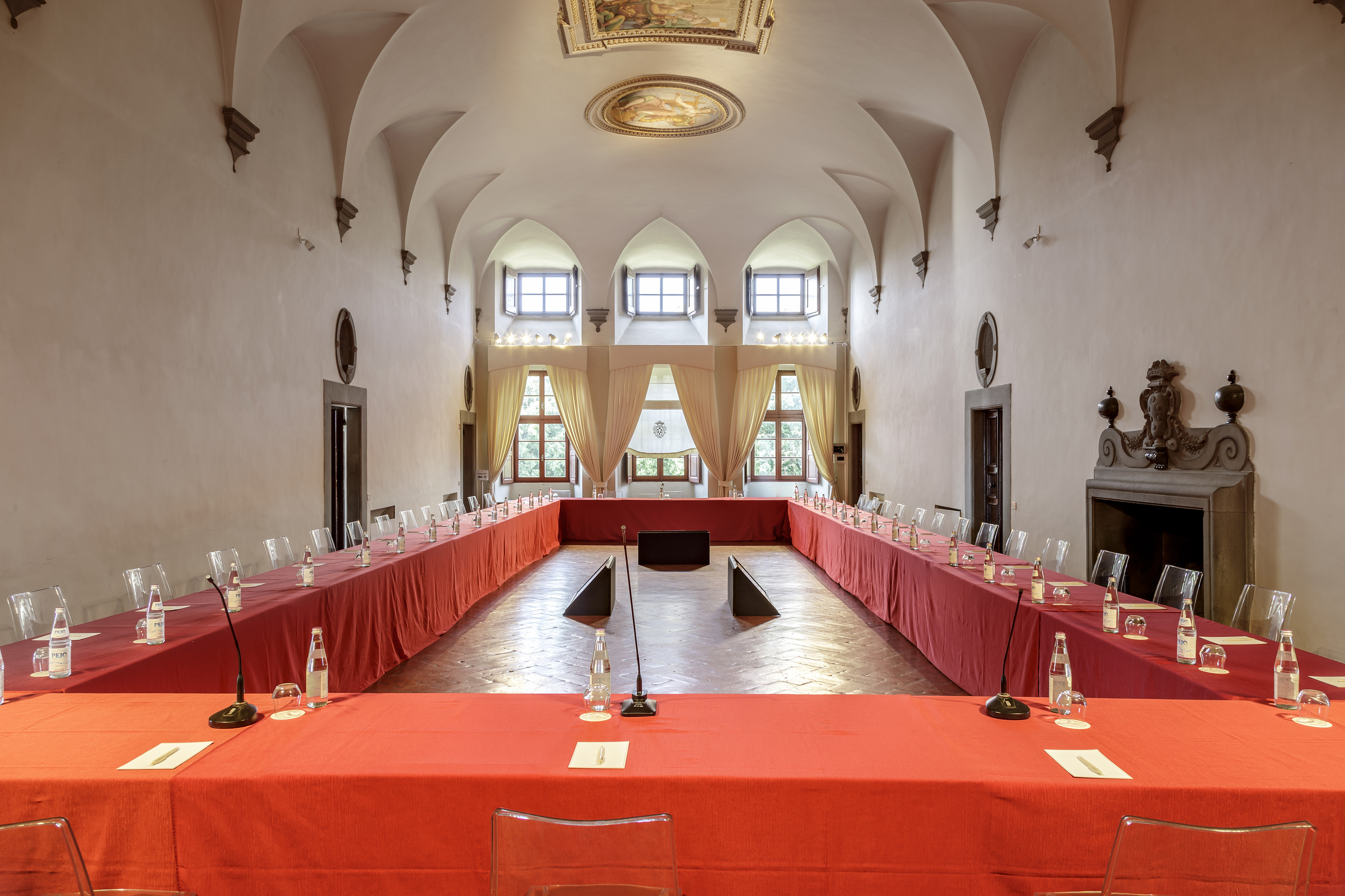 Historic meeting room, U-shaped table, red linens, vaulted ceiling, frescoes.