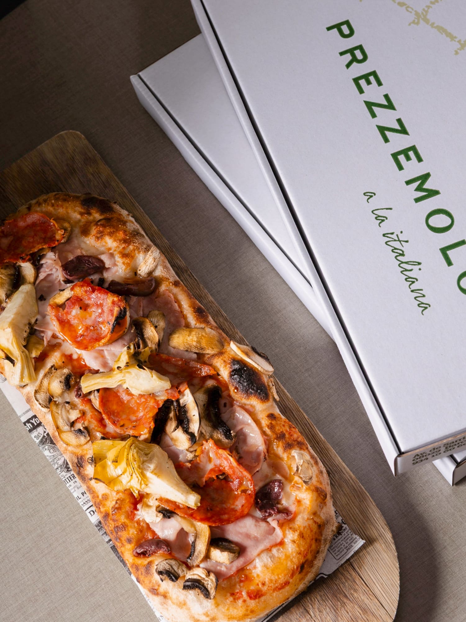 a pizza on a wood board next to a box