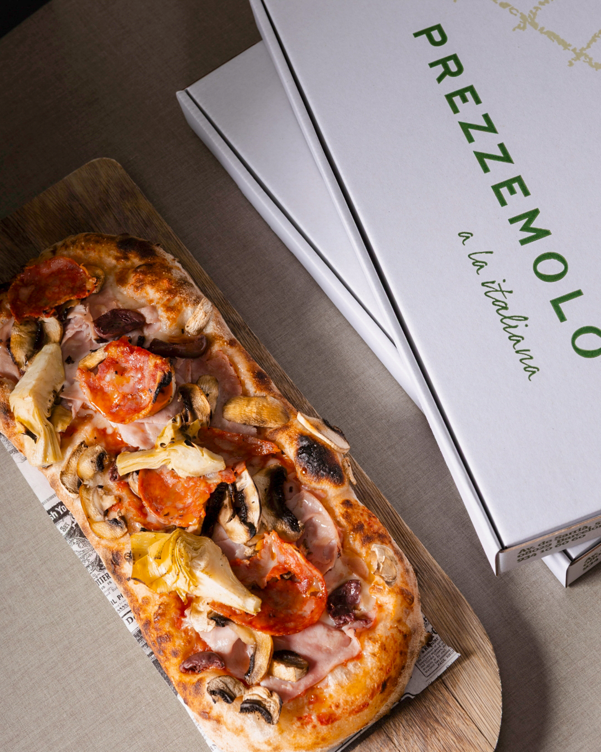 a pizza on a wood board next to a box