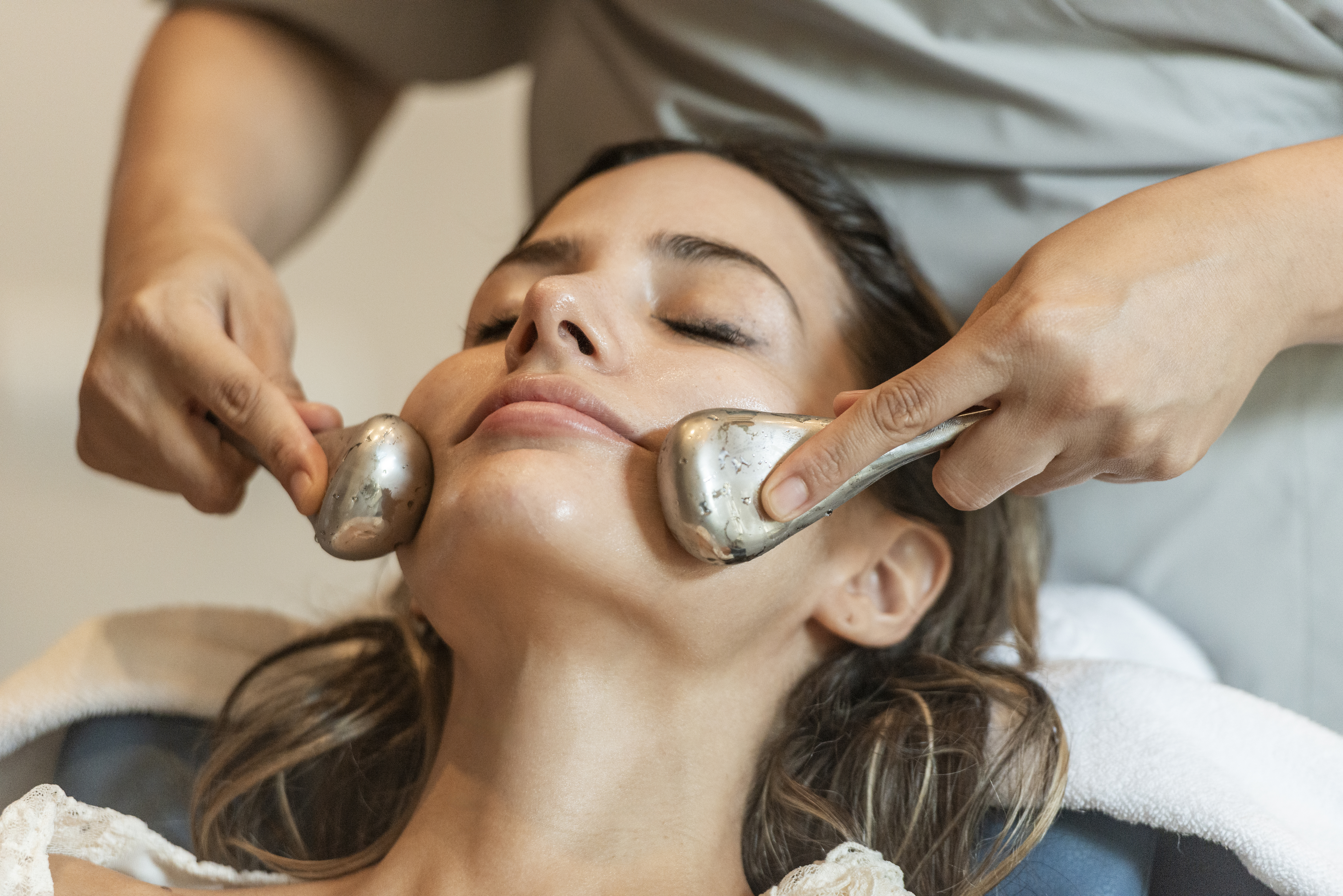 Relaxed woman receiving cryo facial with ice globes at a spa.