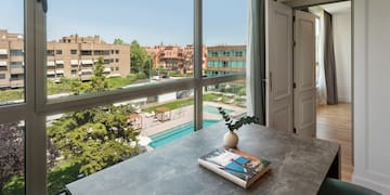 a table with a book on it and a window with a view of a pool and trees