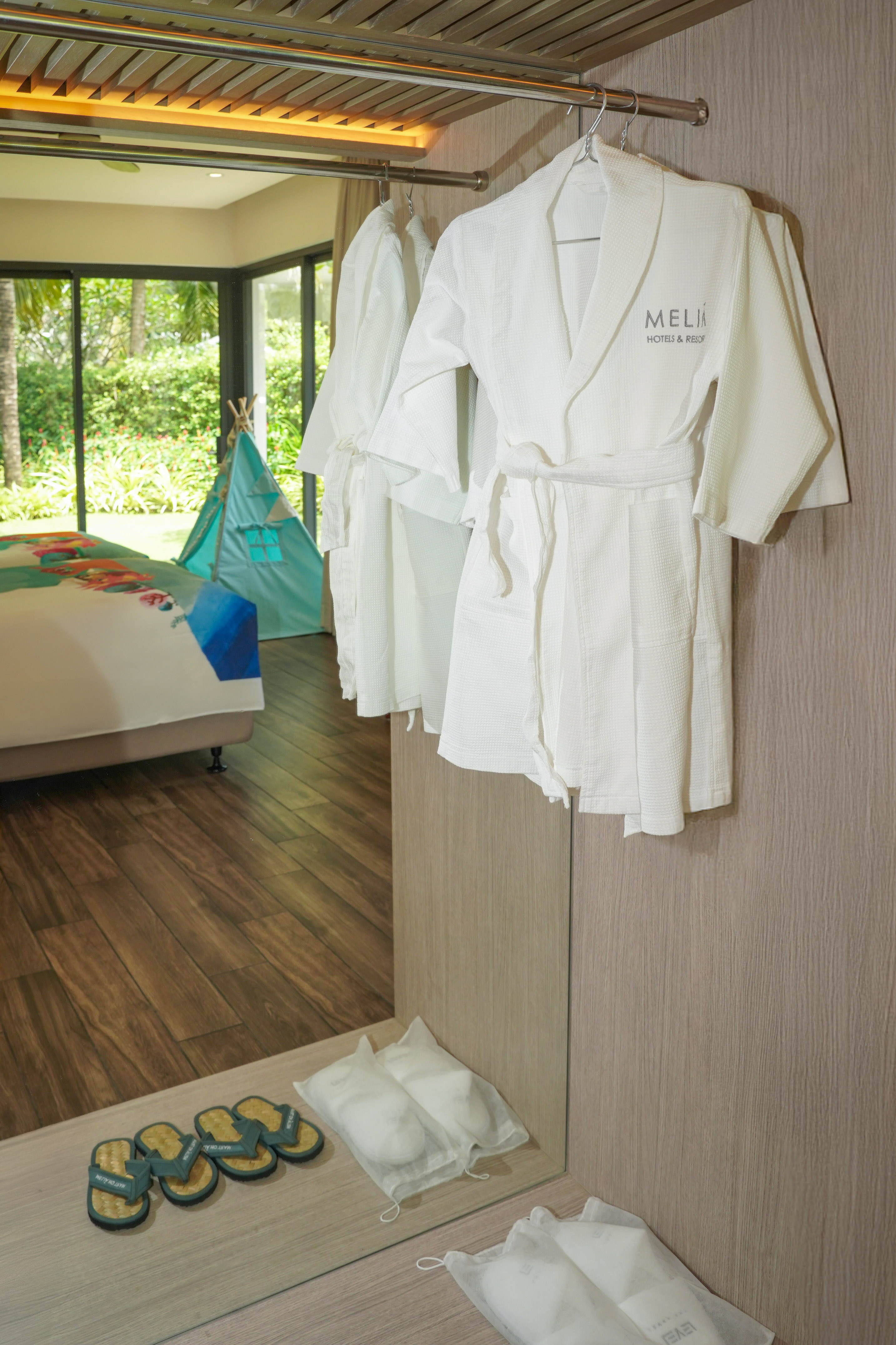 White Meliá resort bathrobes, slippers, and kids tent in a luxury hotel room.
