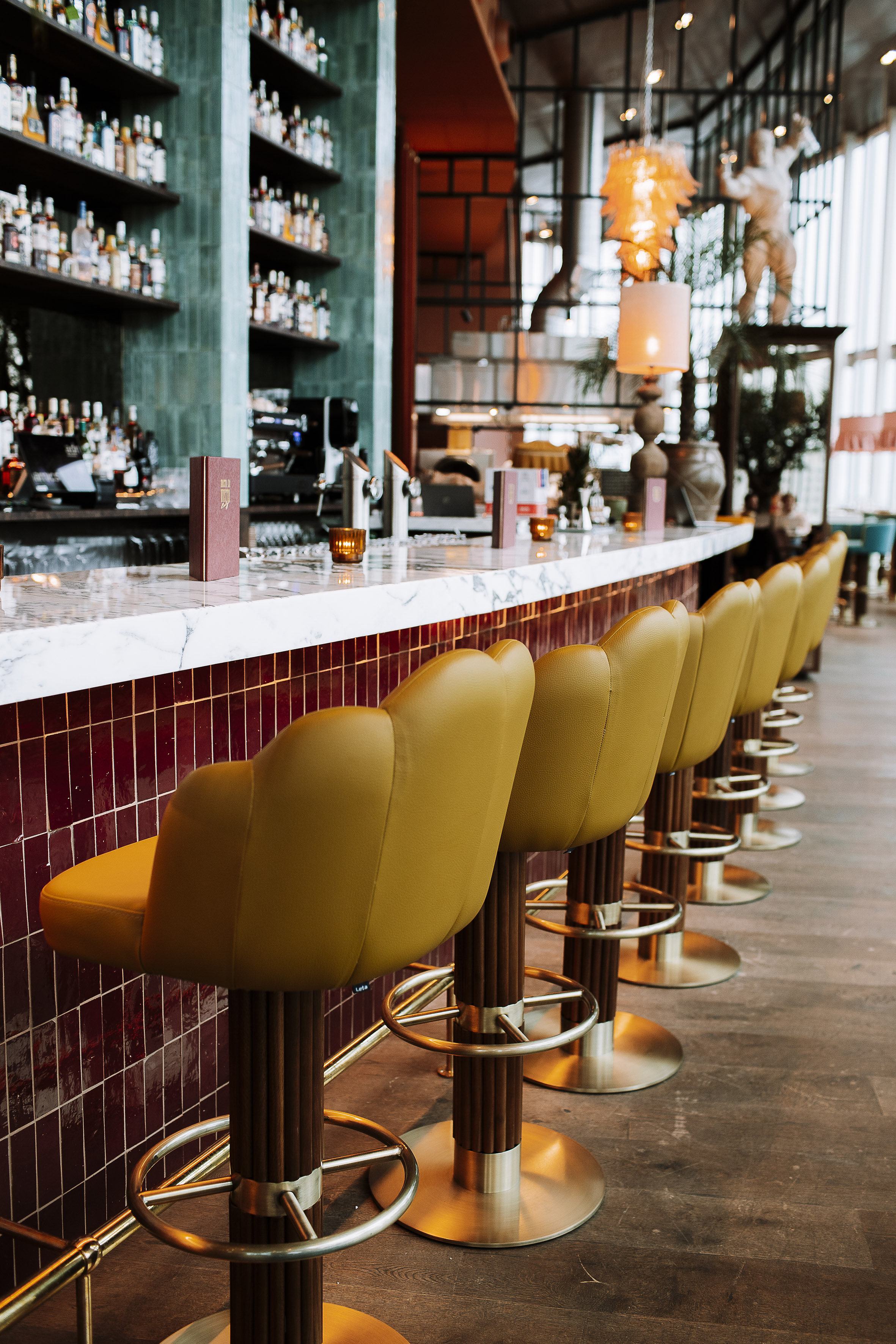 Modern bar, yellow stools, marble counter, liquor bottles.
