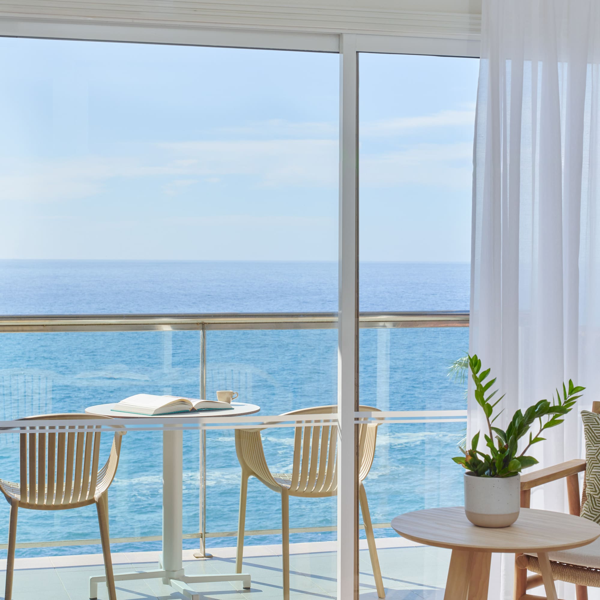 a balcony with a table and chairs and a plant