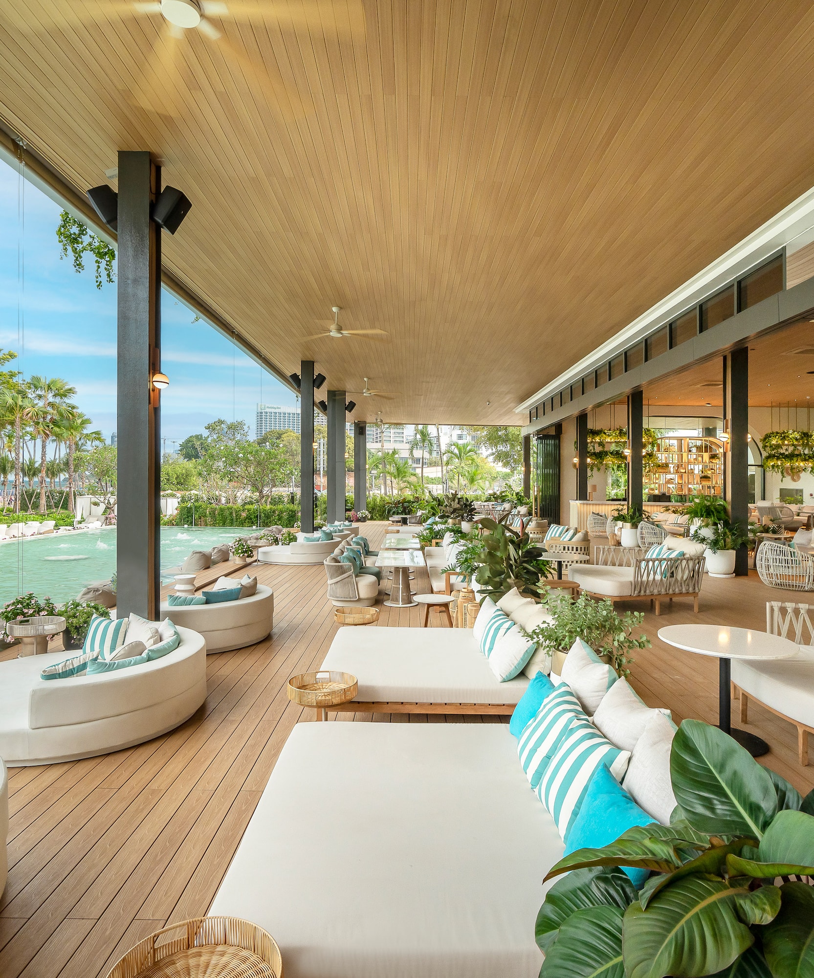 Luxury resort outdoor lounge overlooking beach, pool, with stylish deck seating.