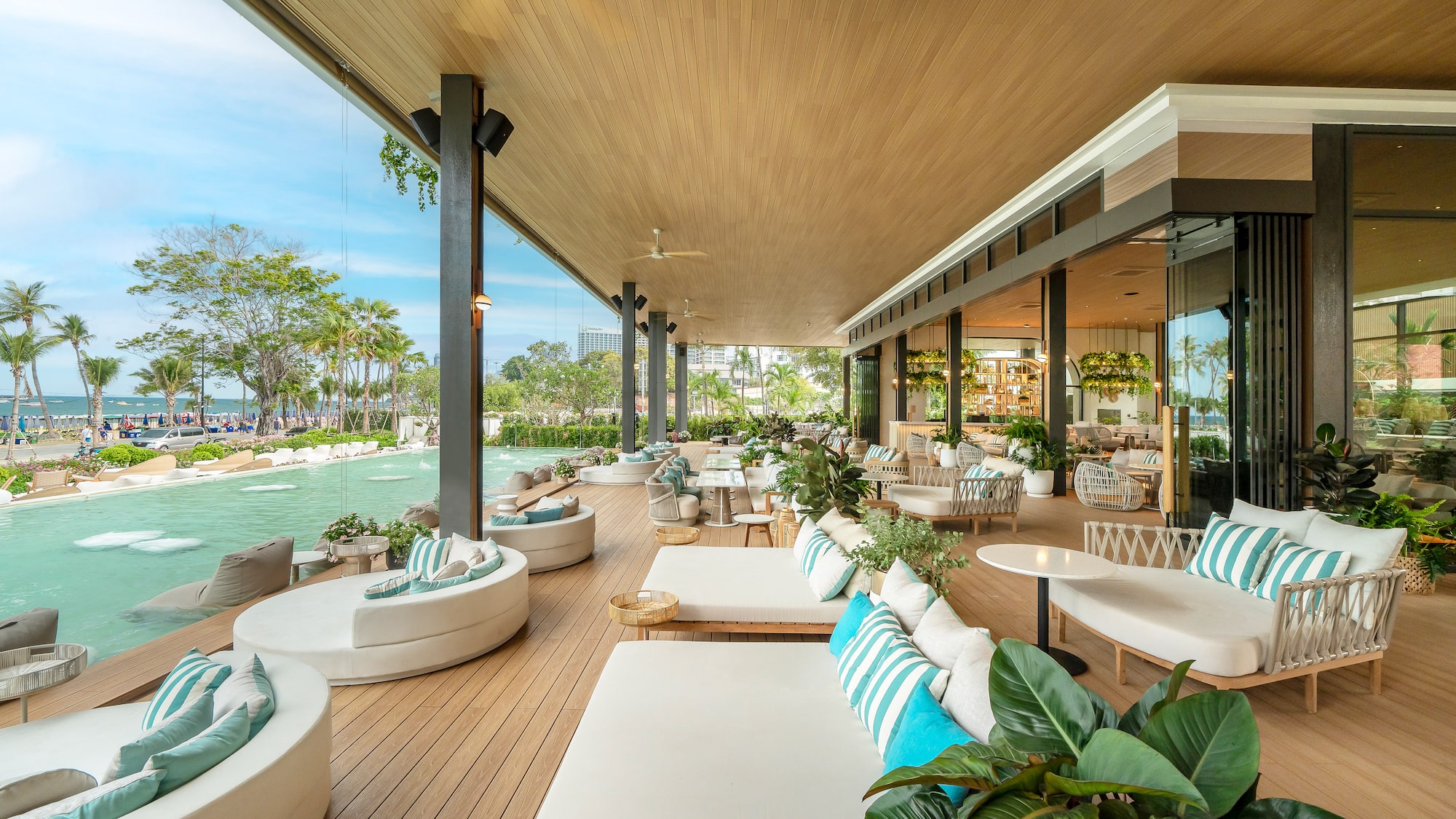 Luxury outdoor resort lounge overlooking pool, beach, and palm trees.