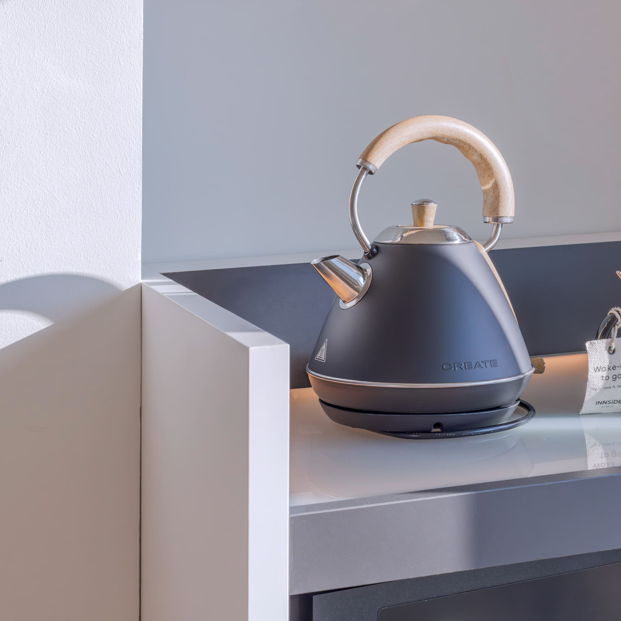 Tetera eléctrica negra, tazas de café/té en mostrador para desayuno.