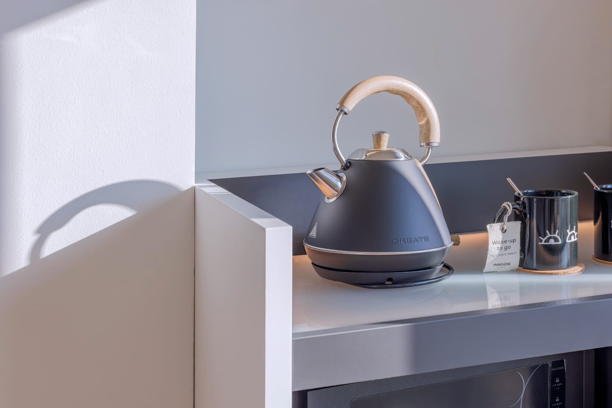 Tetera eléctrica negra, tazas de café/té en mostrador para desayuno.