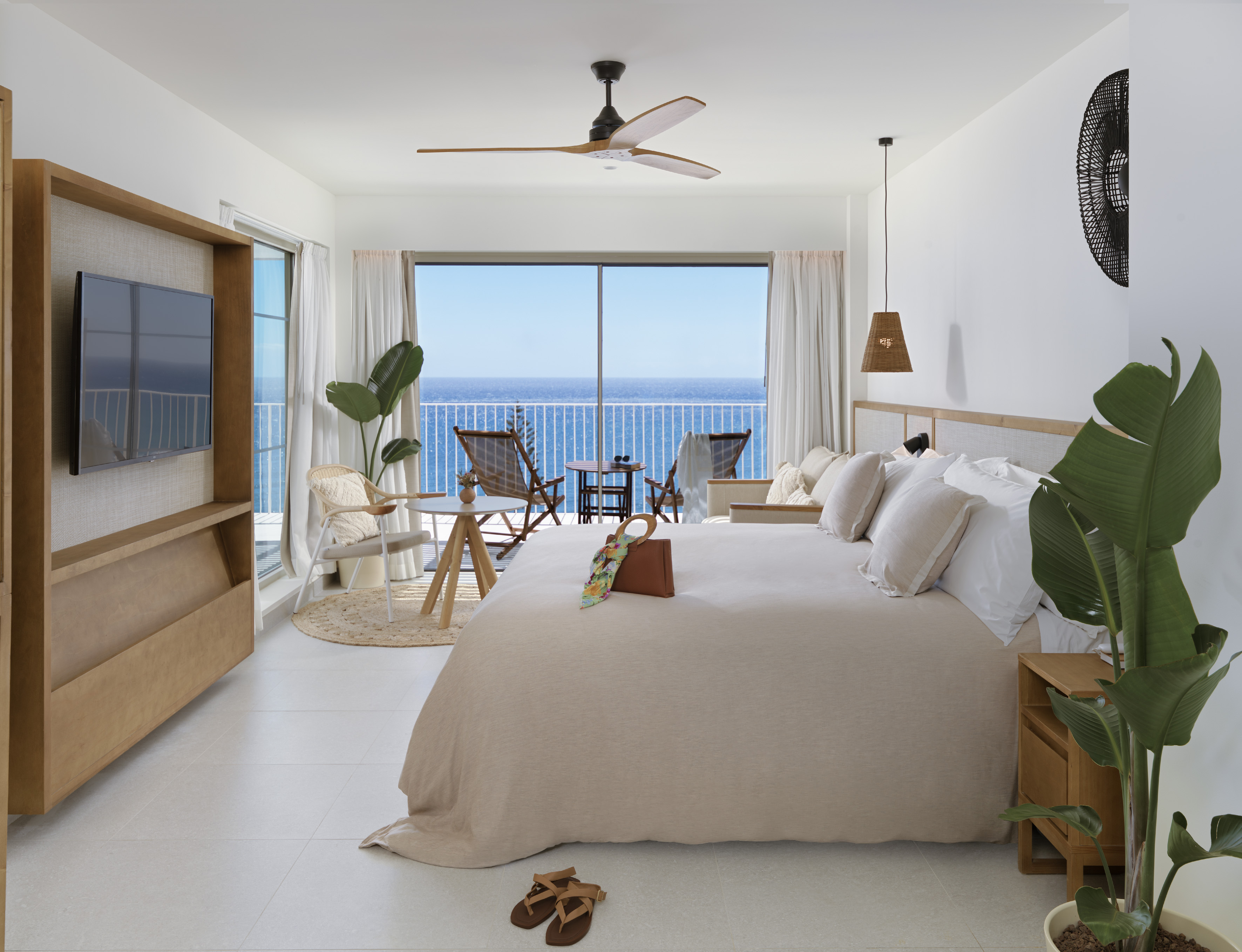 Coastal hotel bedroom with ocean view balcony, large bed, and modern decor.