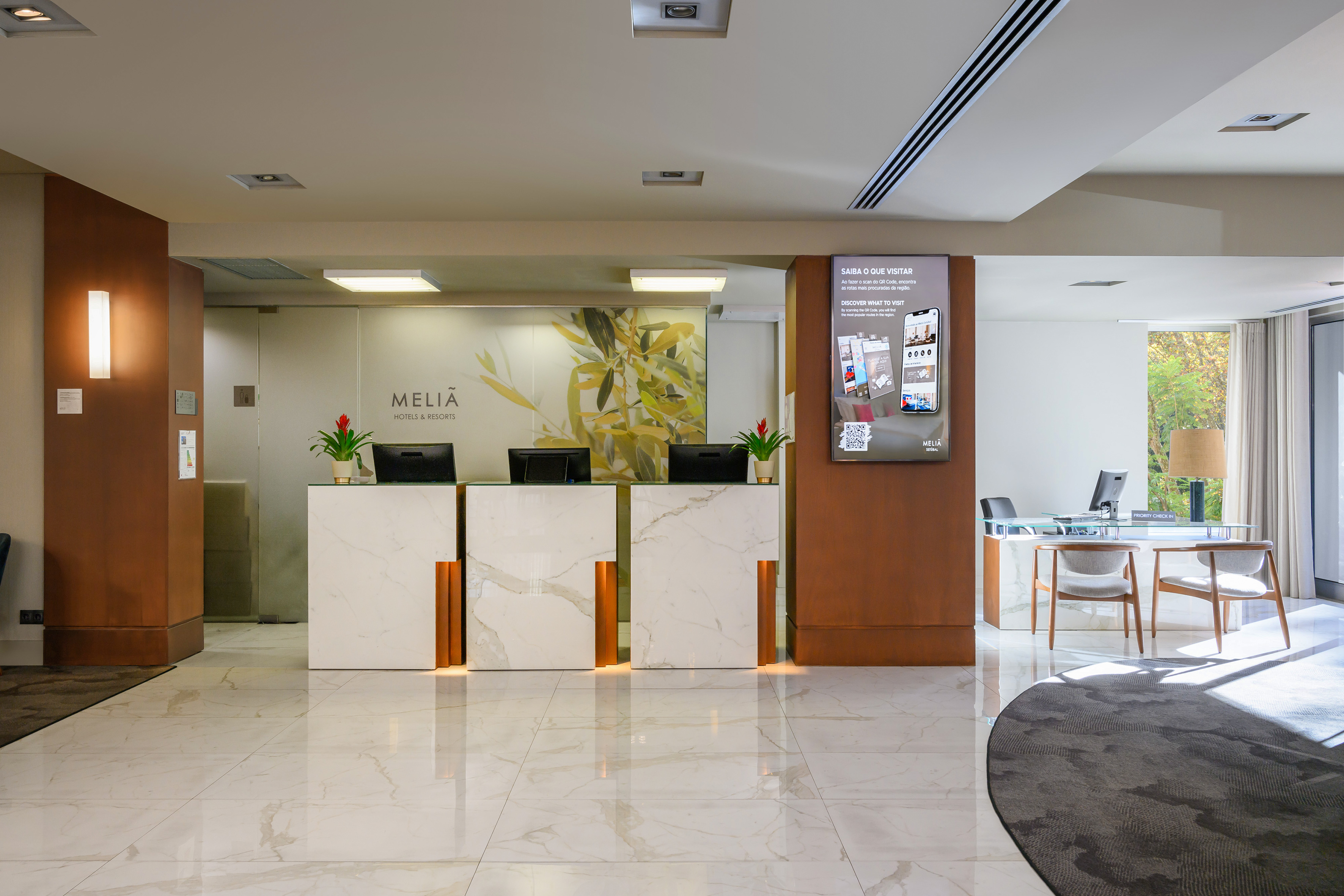 Meliã hotel reception area with three modern marble desks and digital screen.