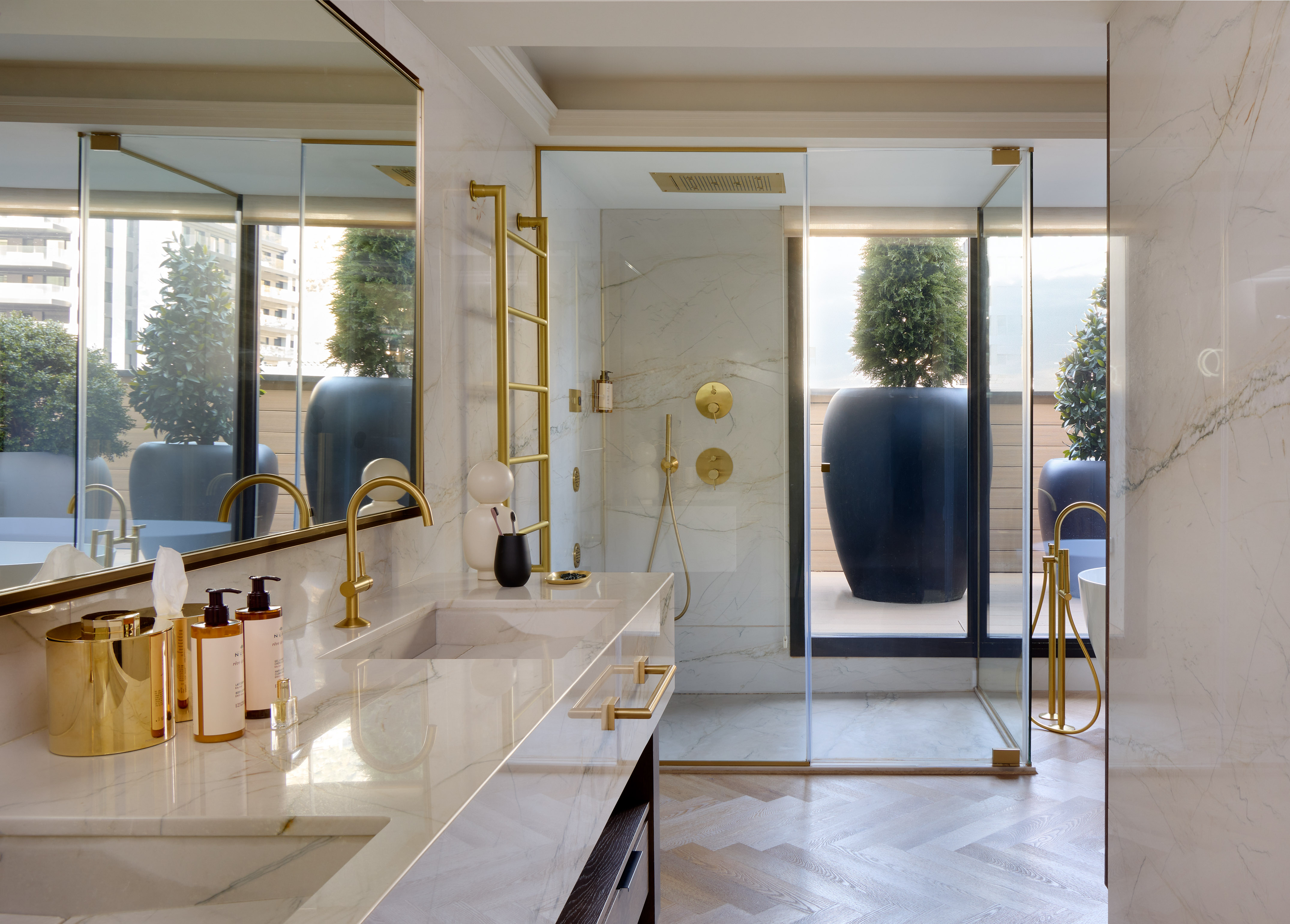 Luxury modern bathroom with marble double vanity, gold fixtures, and walk-in shower.
