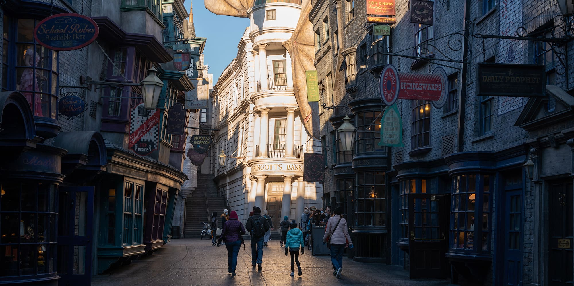 people walking down a street with buildings and a dragon statue