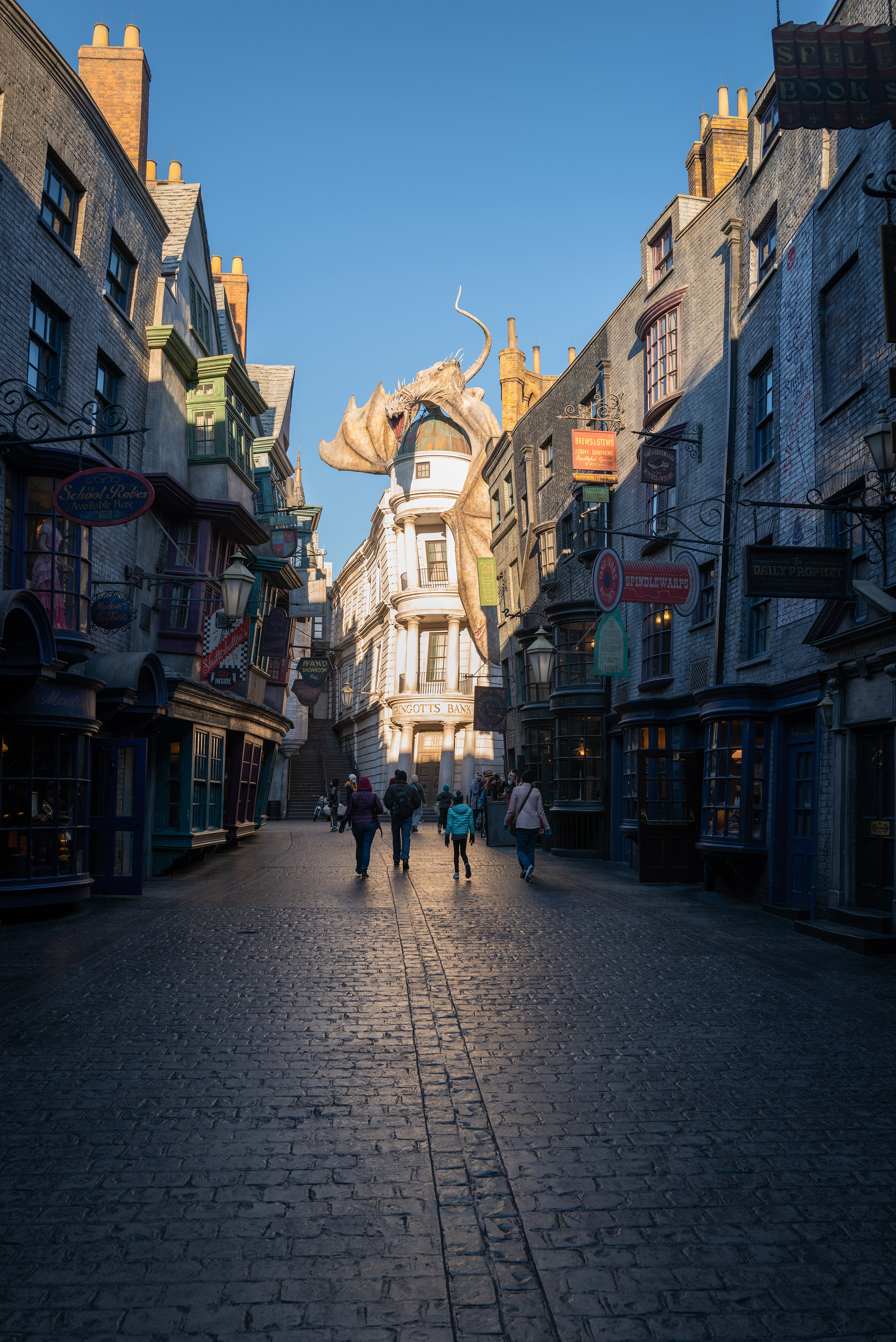 people walking down a street with buildings and a dragon statue