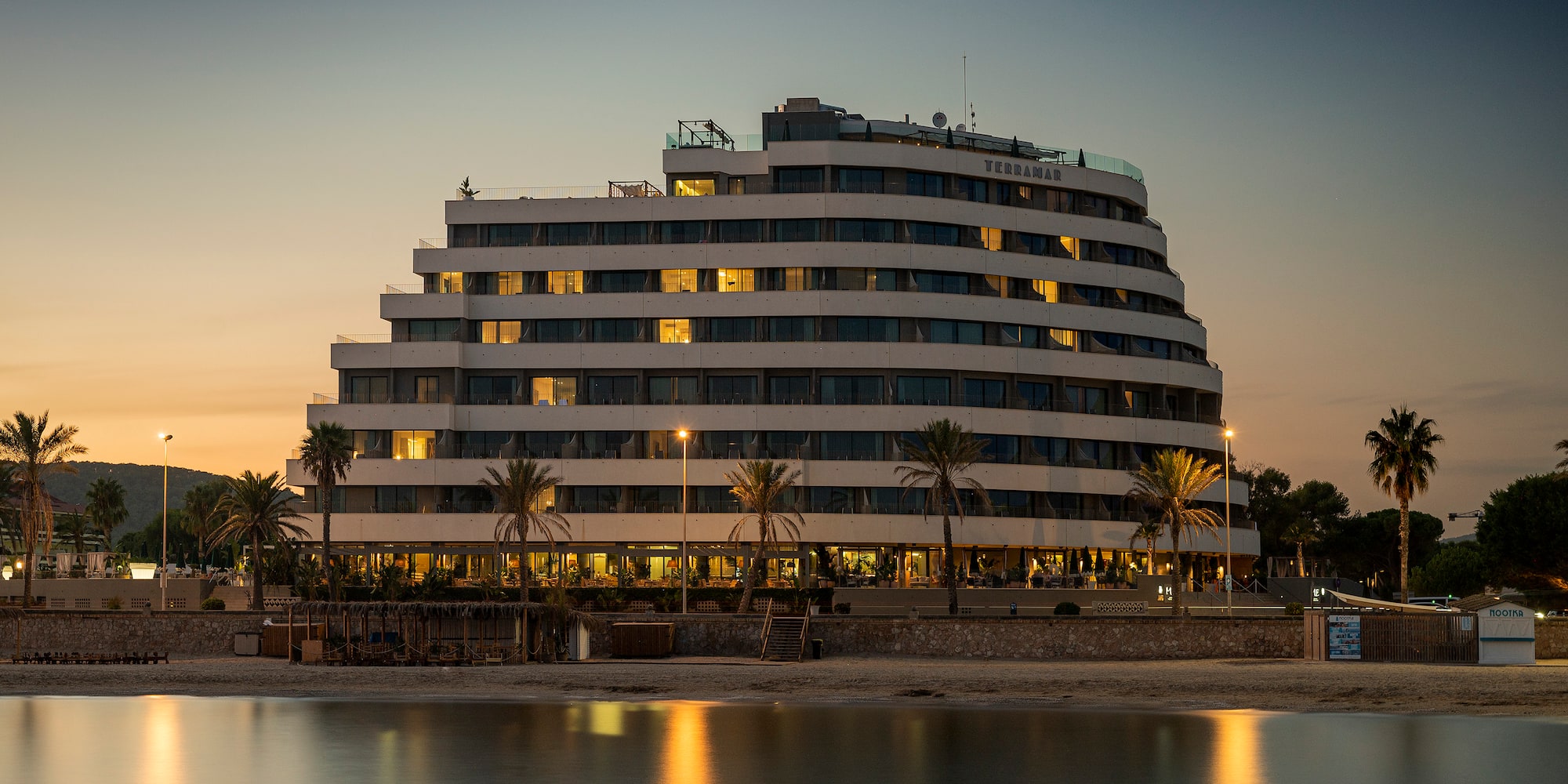 a building with many windows and palm trees on the side of it