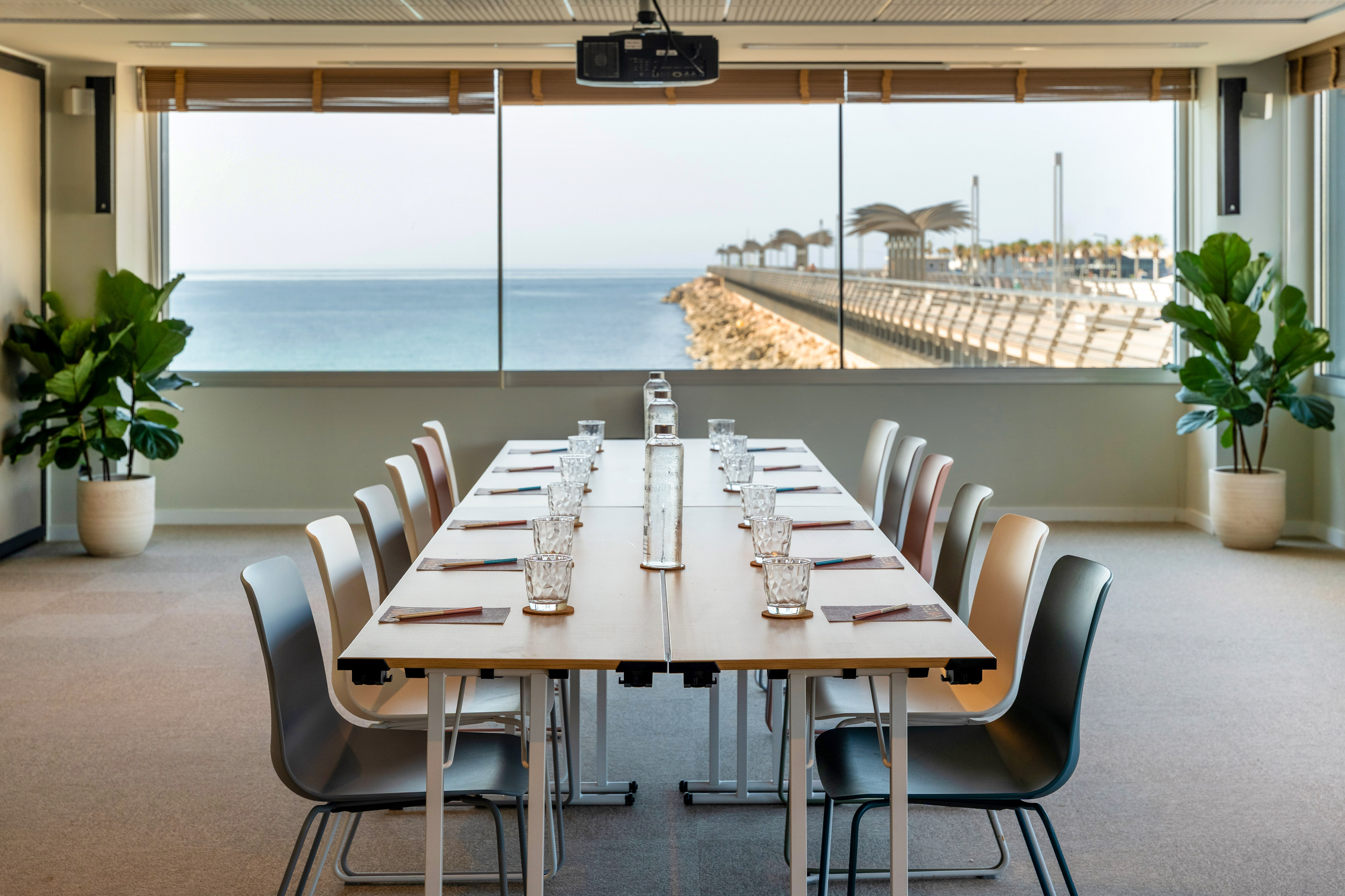 Coastal meeting room with panoramic sea view, long table, and modern chairs.