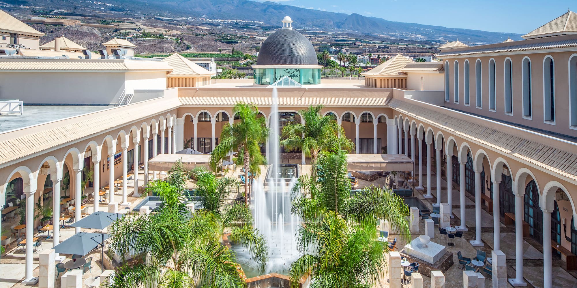 a fountain in a courtyard with palm trees