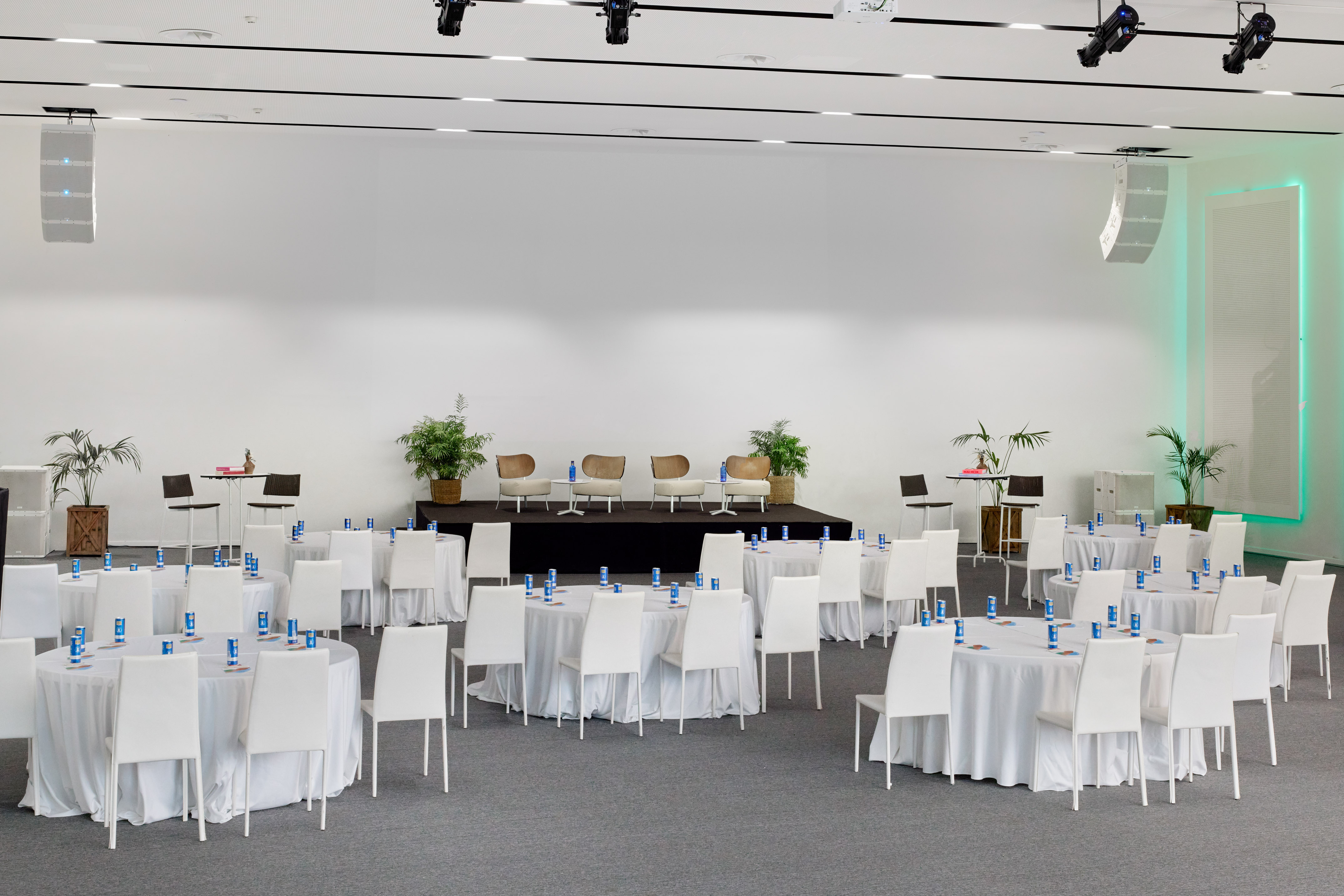 Spacious conference room with round tables, white chairs, and stage.
