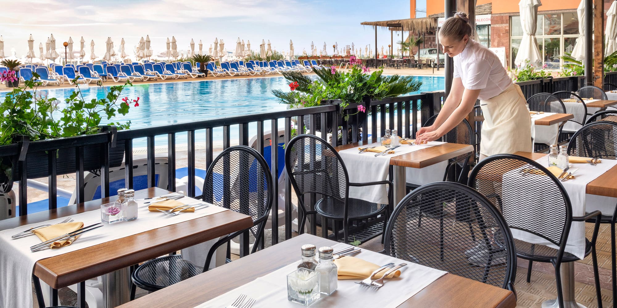 a woman standing at tables outside of a restaurant