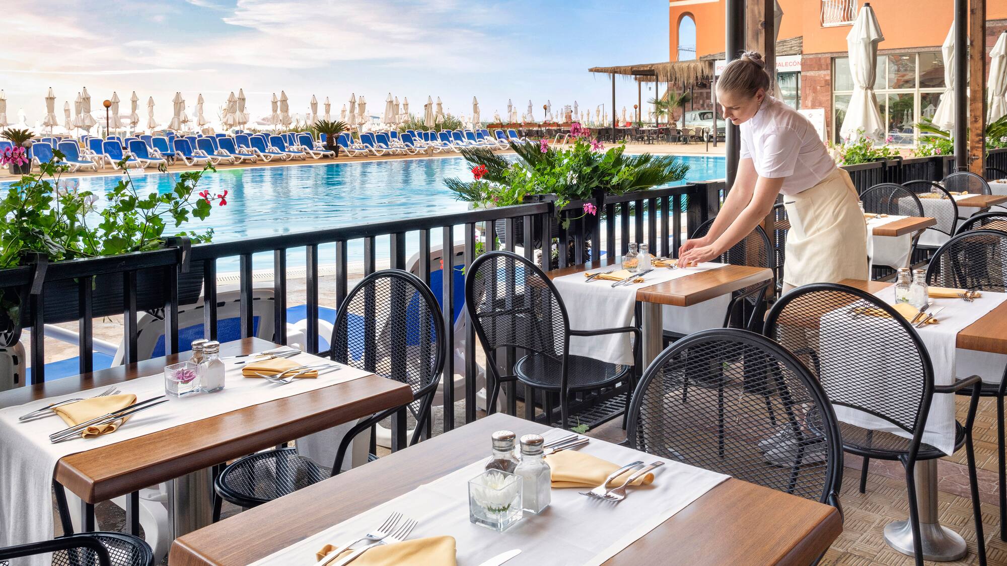 a woman standing at tables outside of a restaurant