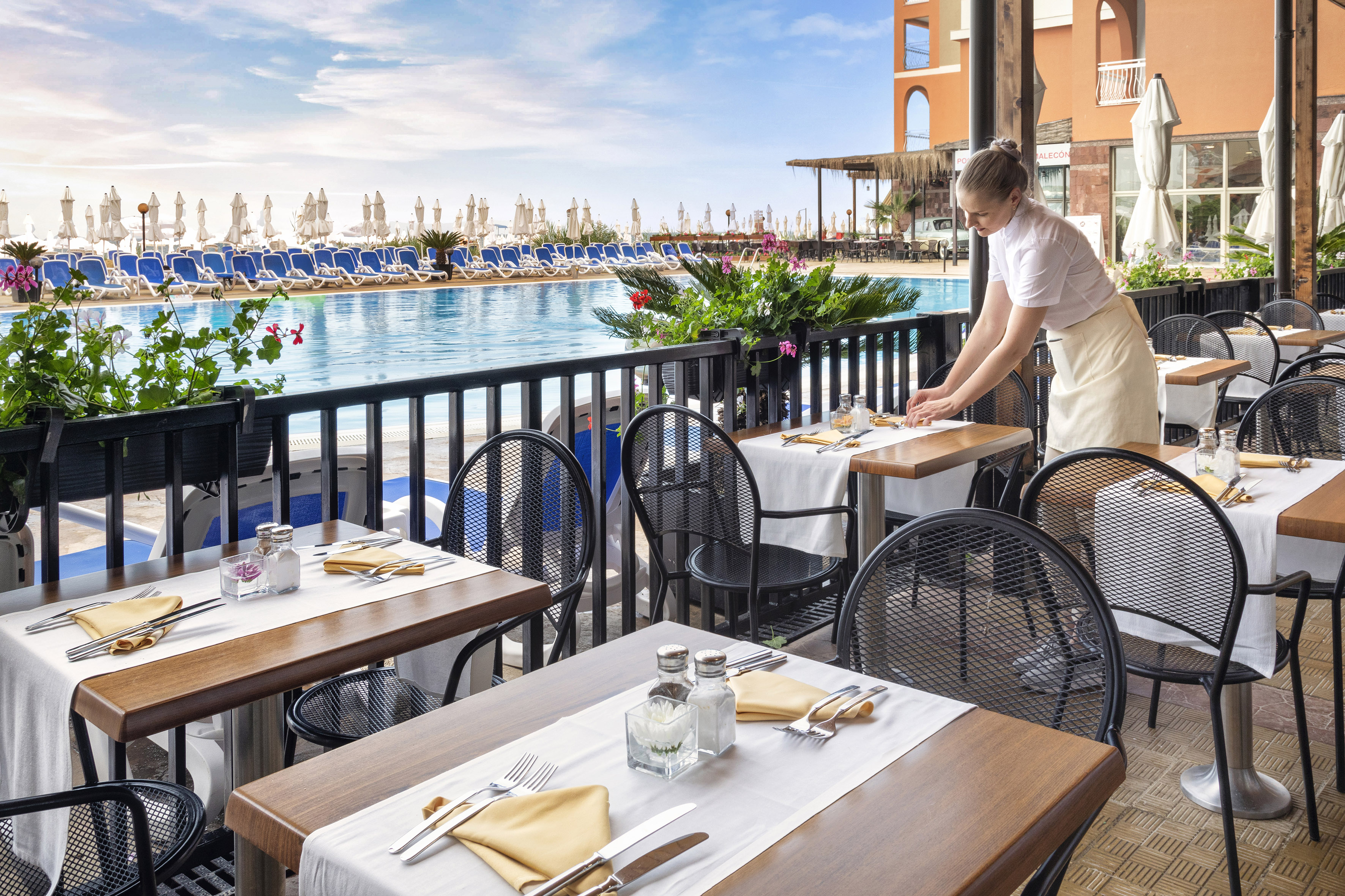 a woman standing at tables outside of a restaurant