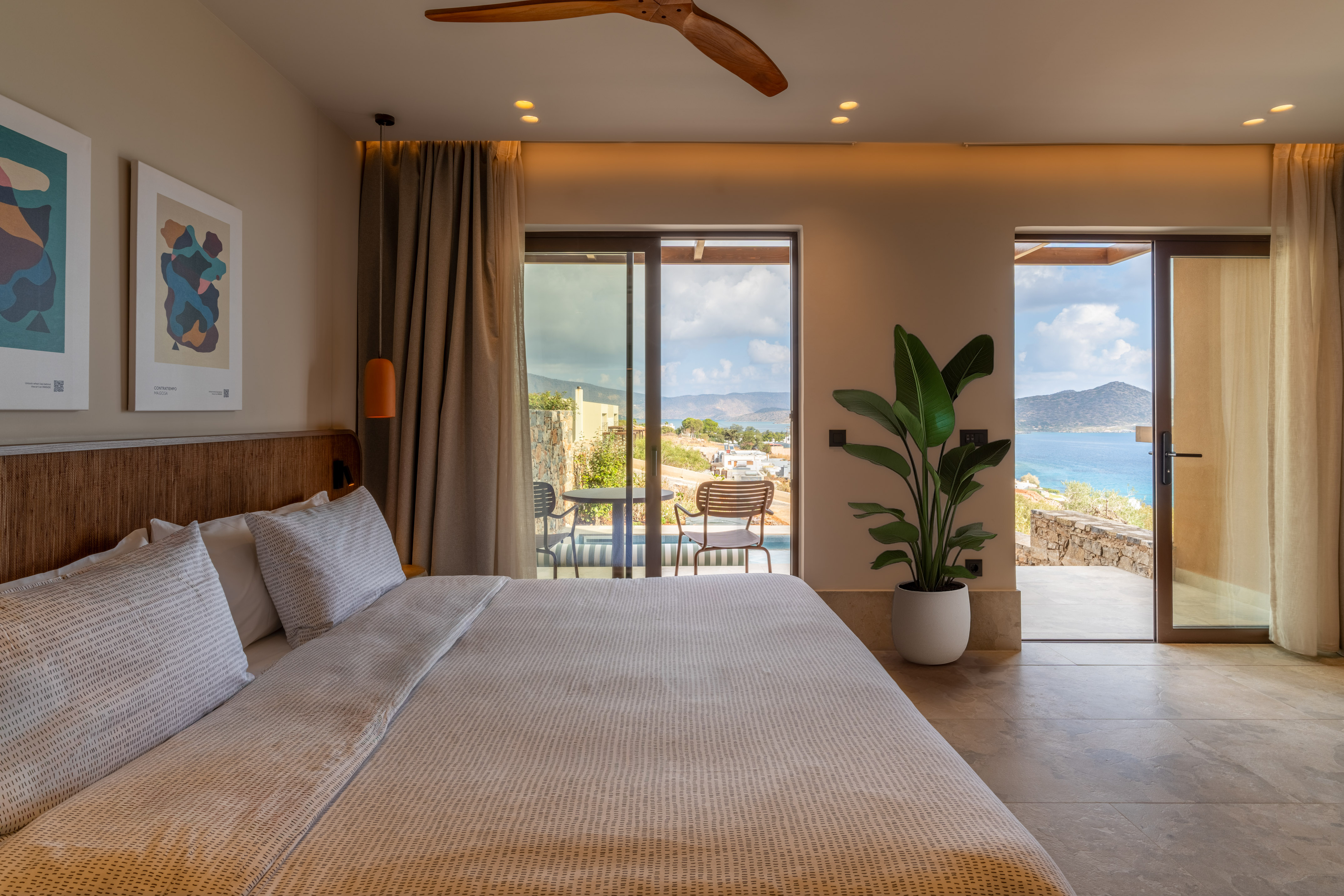 Luxury bedroom with sea view balcony, large bed, and modern coastal design.