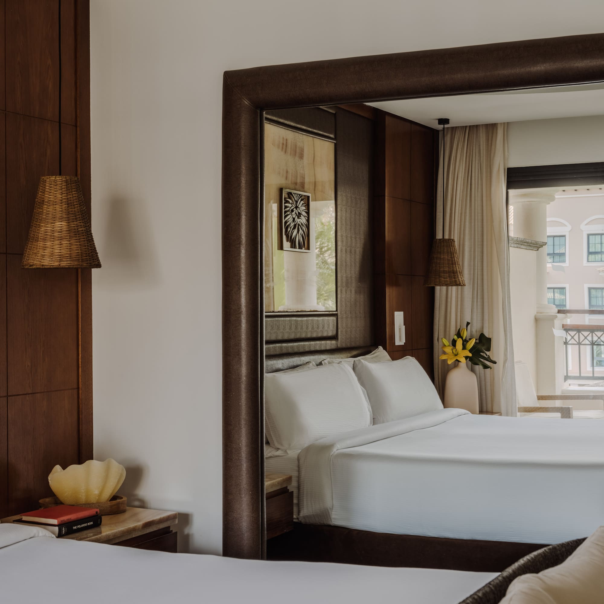 a bedroom with white beds and a mirror