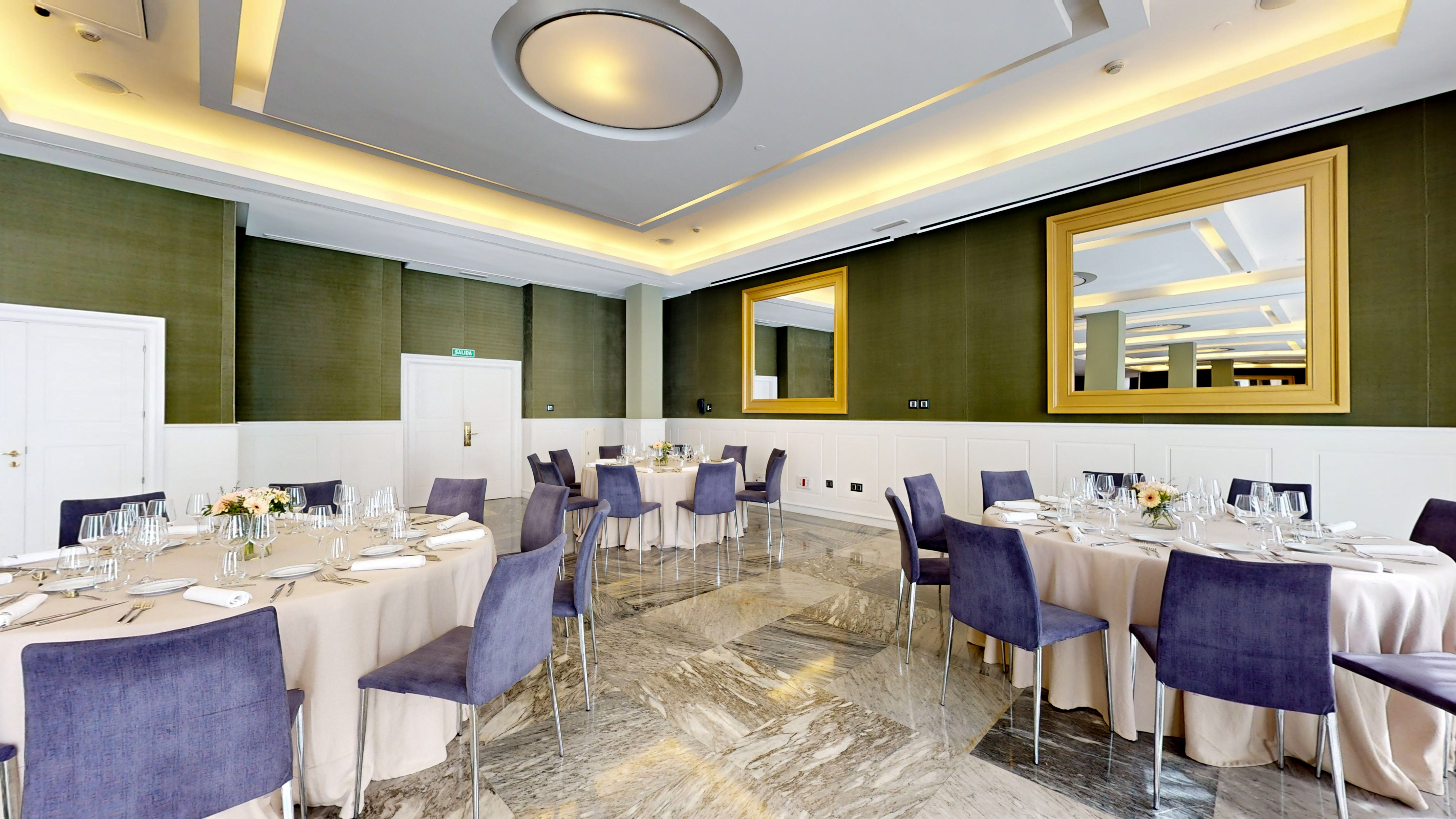Formal event space with set dining tables, purple chairs, green walls, gold mirrors.