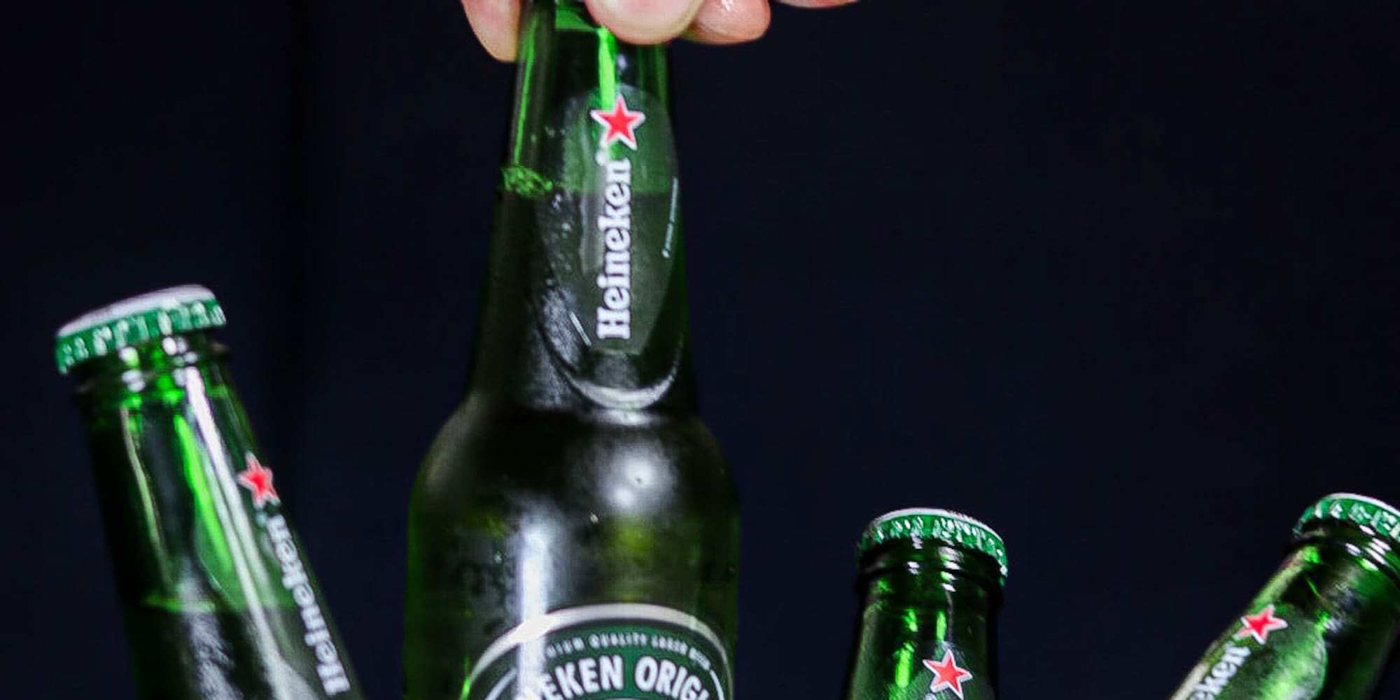 a hand holding a bottle of beer in a bucket of ice