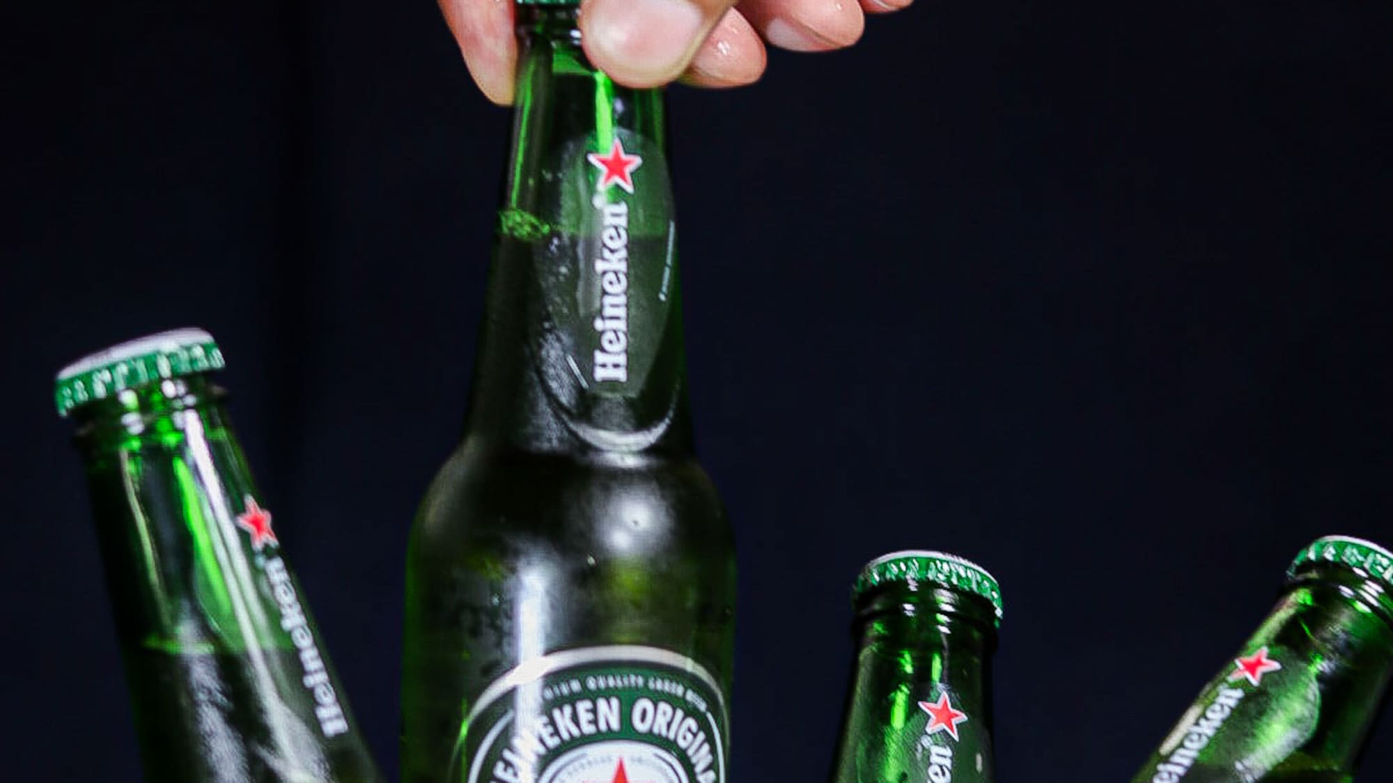 a hand holding a bottle of beer in a bucket of ice