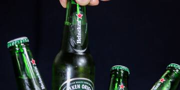 a hand holding a bottle of beer in a bucket of ice