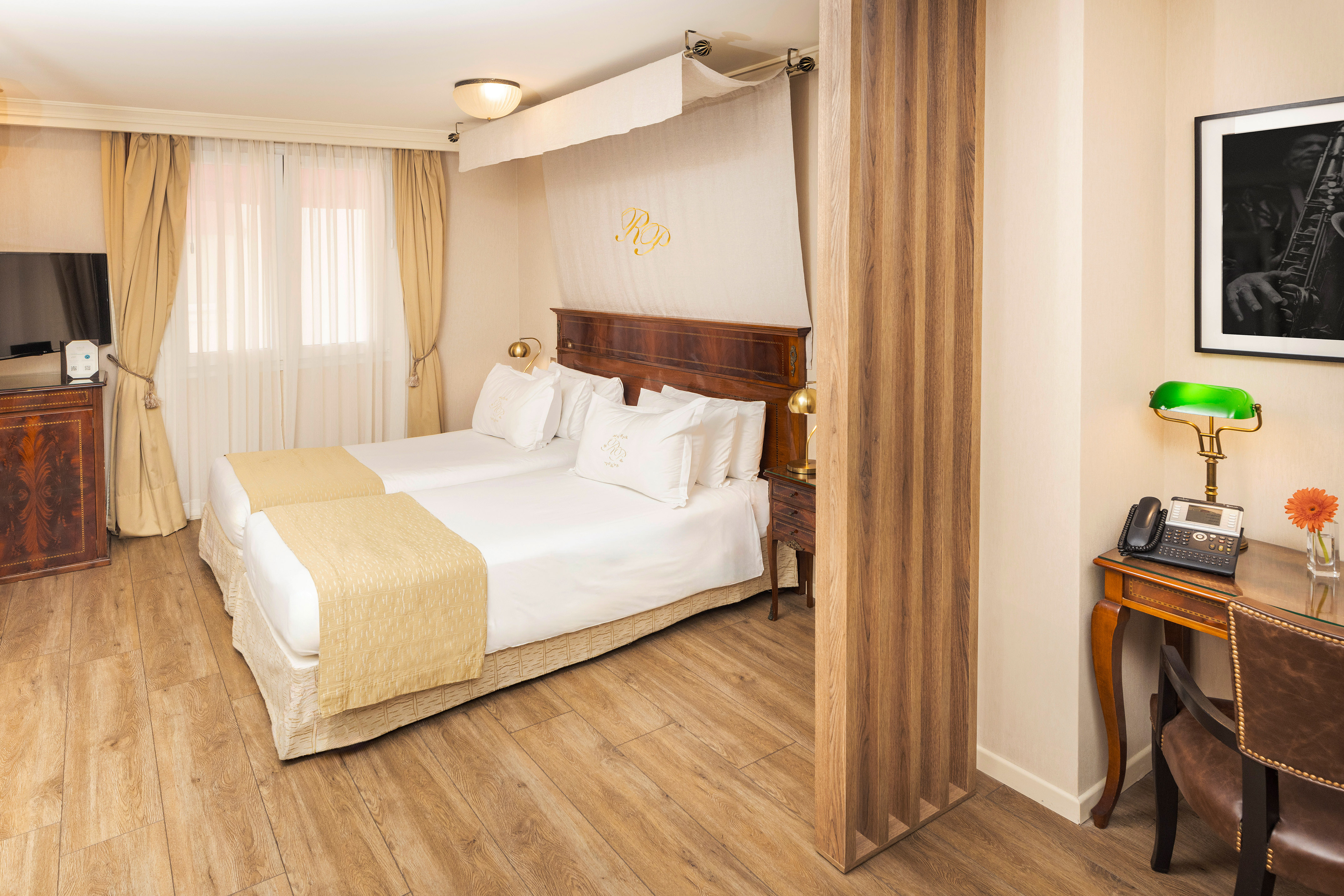 Elegant hotel room with twin beds, wood floor, classic furnishings, and desk.