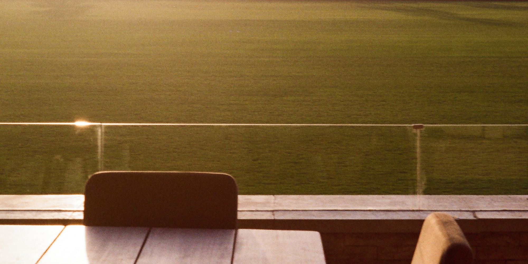 a table and chairs outside with a grass field in the background
