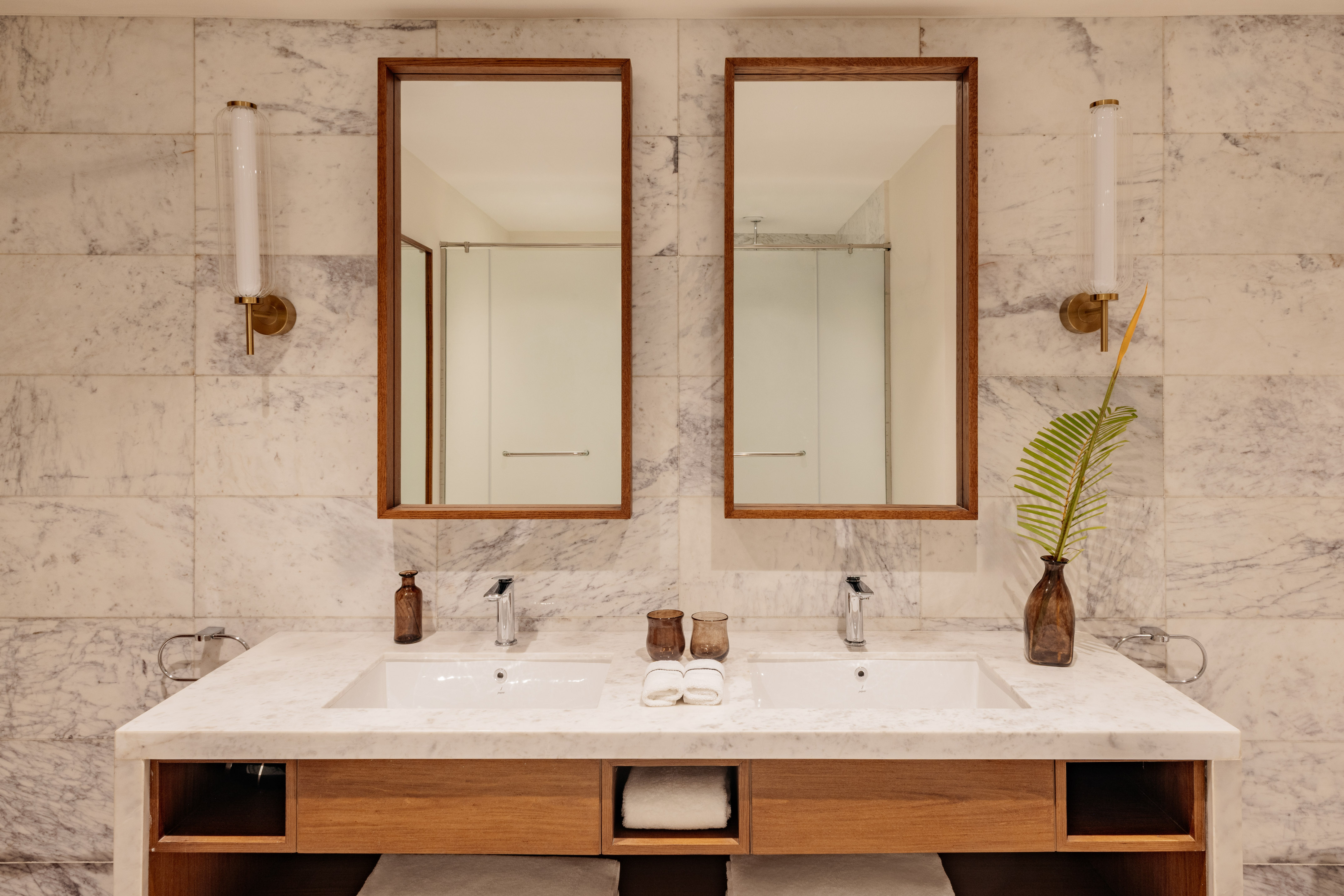 Modern double sink marble bathroom vanity with wood accents and framed mirrors.