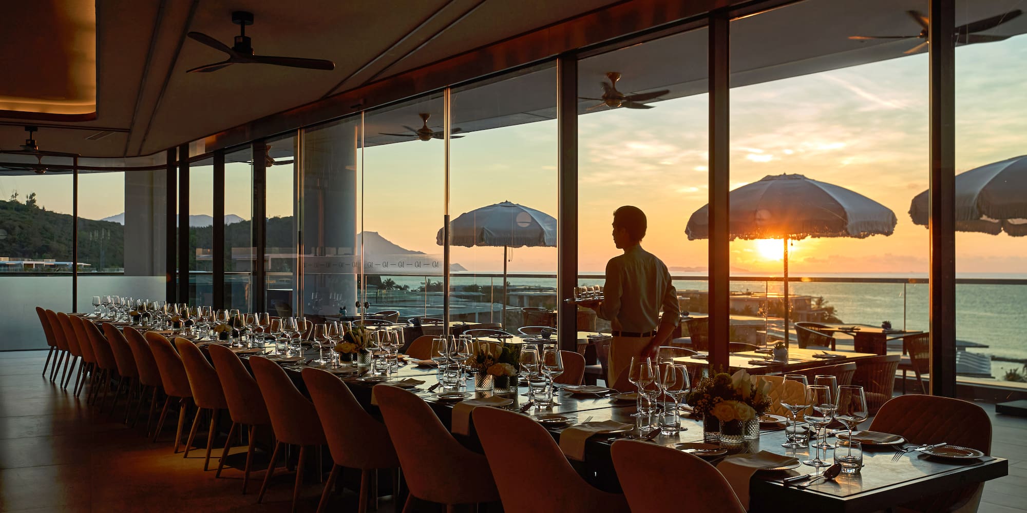 a man standing at a table with chairs and umbrellas