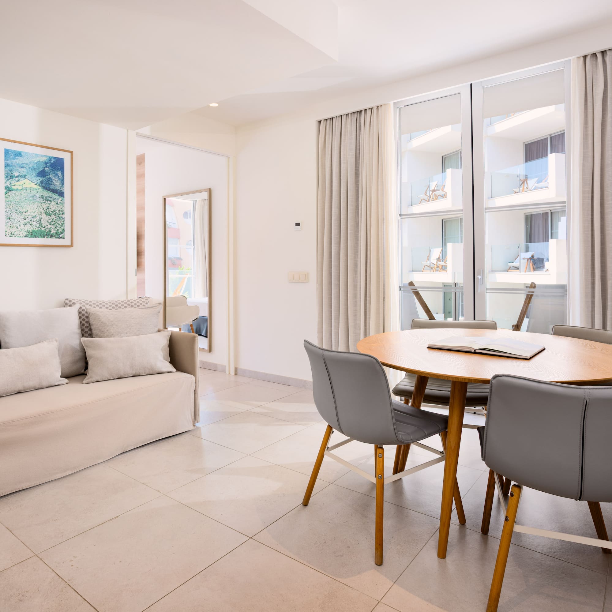 Bright studio apartment with sofa, dining table, and balcony access.