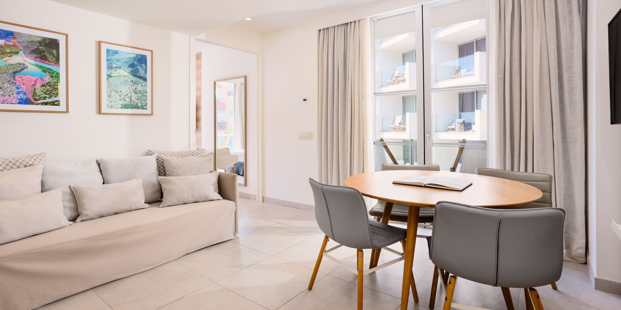 Bright studio apartment with sofa, dining table, and balcony access.
