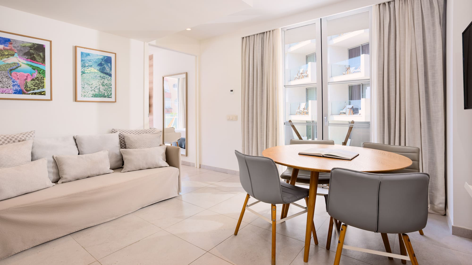 Bright studio apartment with sofa, dining table, and balcony access.