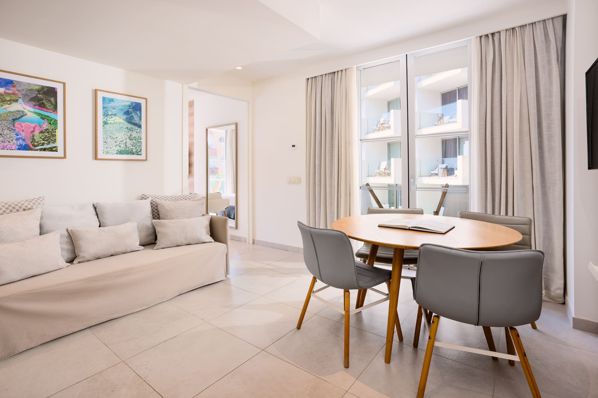 Bright studio apartment with sofa, dining table, and balcony access.