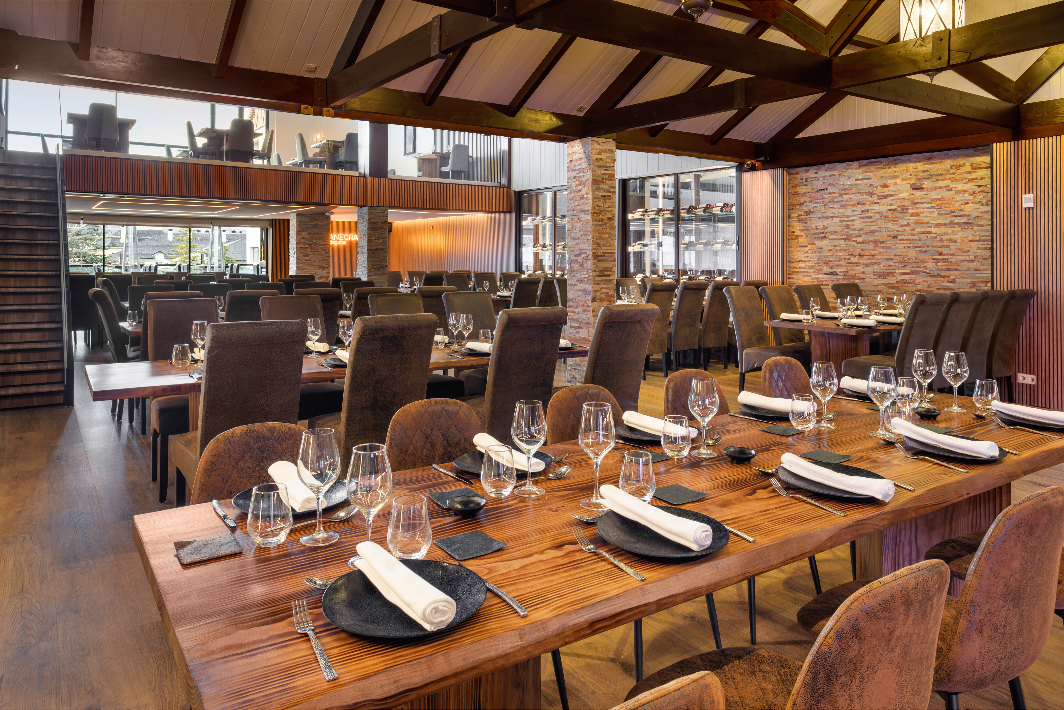 Spacious modern rustic restaurant interior with long wooden tables and high ceilings.