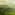 Misty sunrise over rolling green tea plantations and distant mountains.