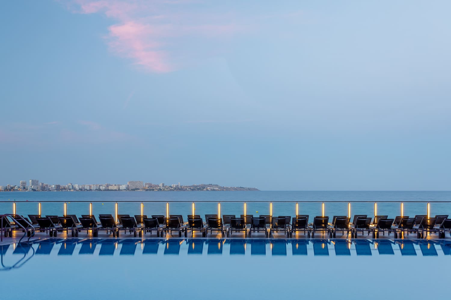 a pool with chairs and a body of water