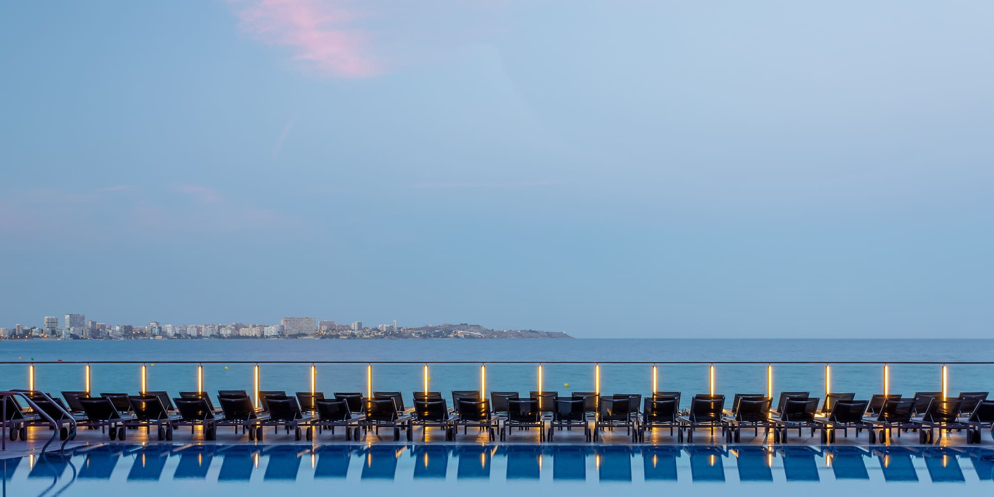 a pool with chairs and a body of water