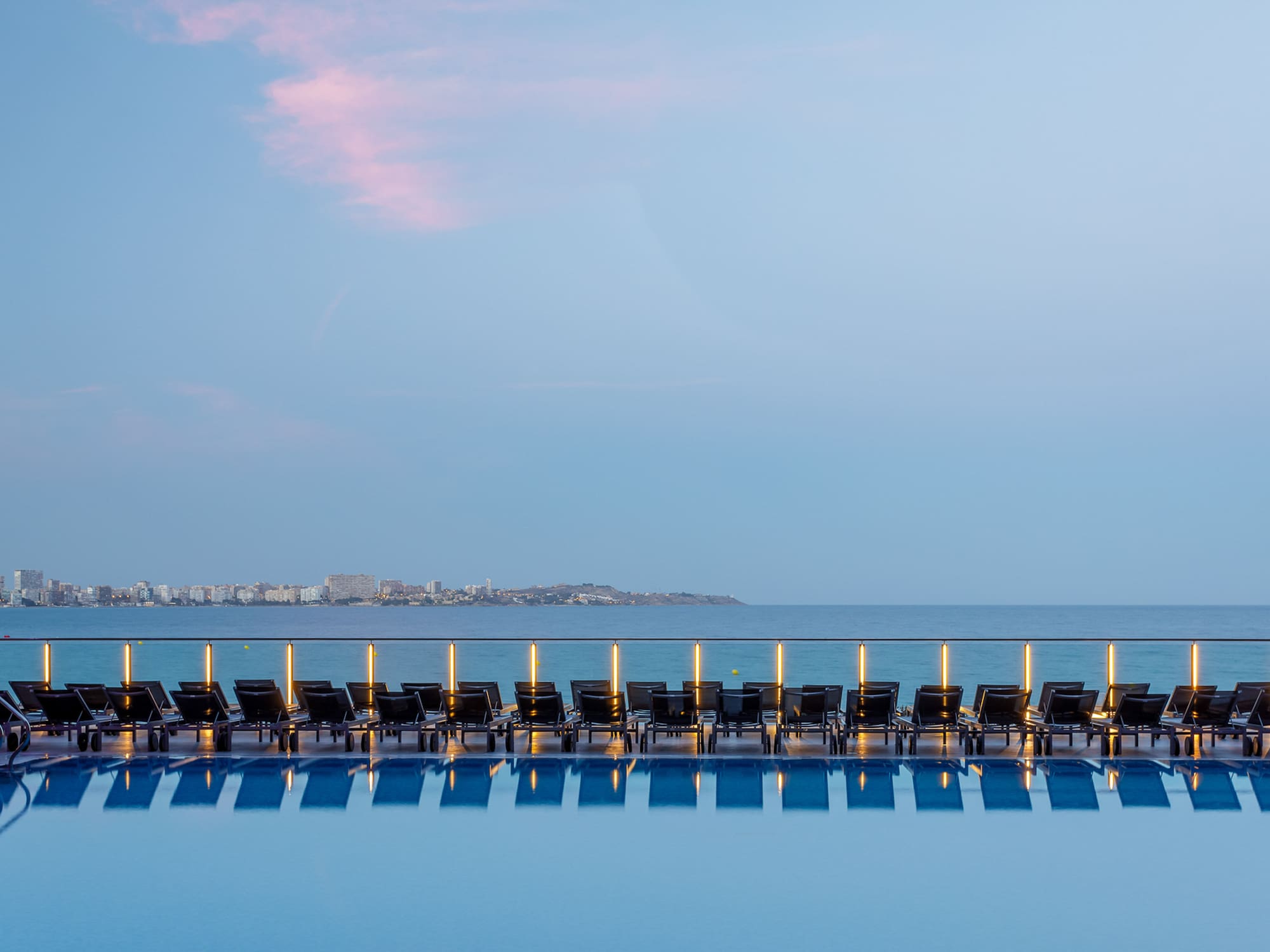 a pool with chairs and a body of water