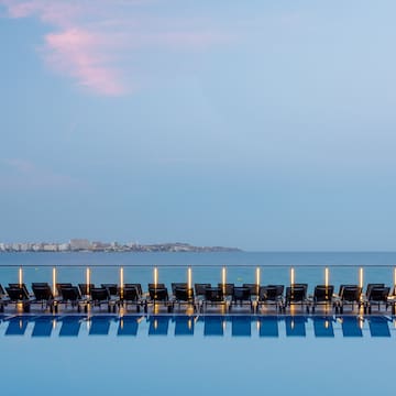 a pool with chairs and a body of water